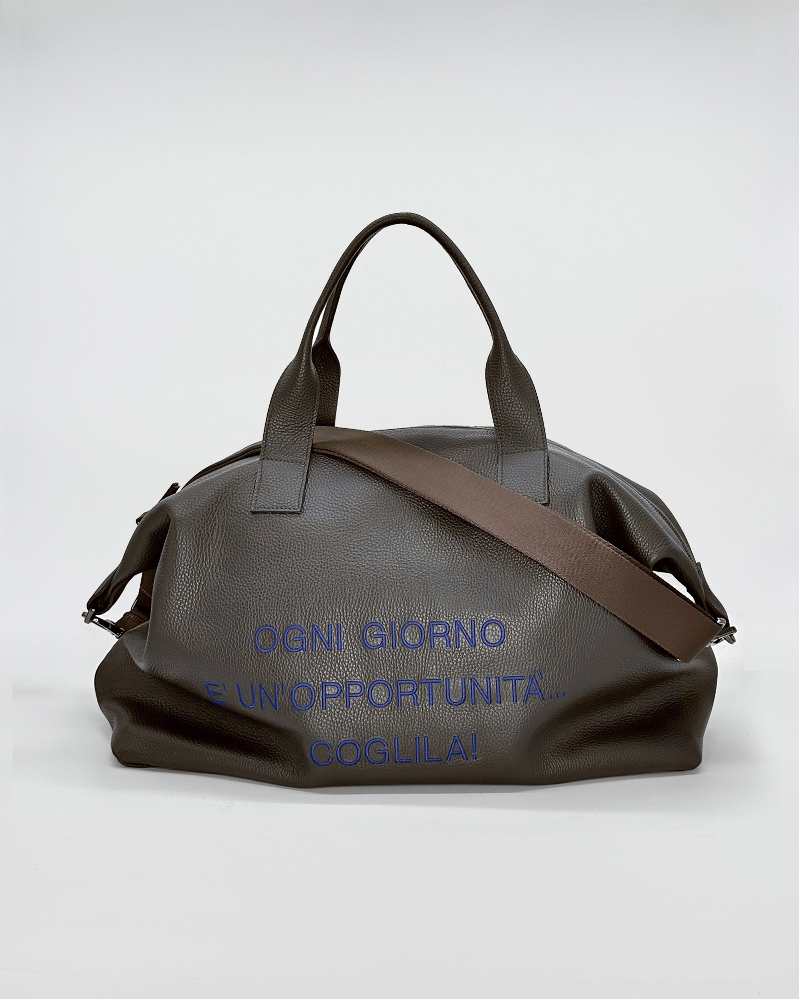 JACK travel bag in dark brown with adjustable shoulder strap and motivational text on the front.
