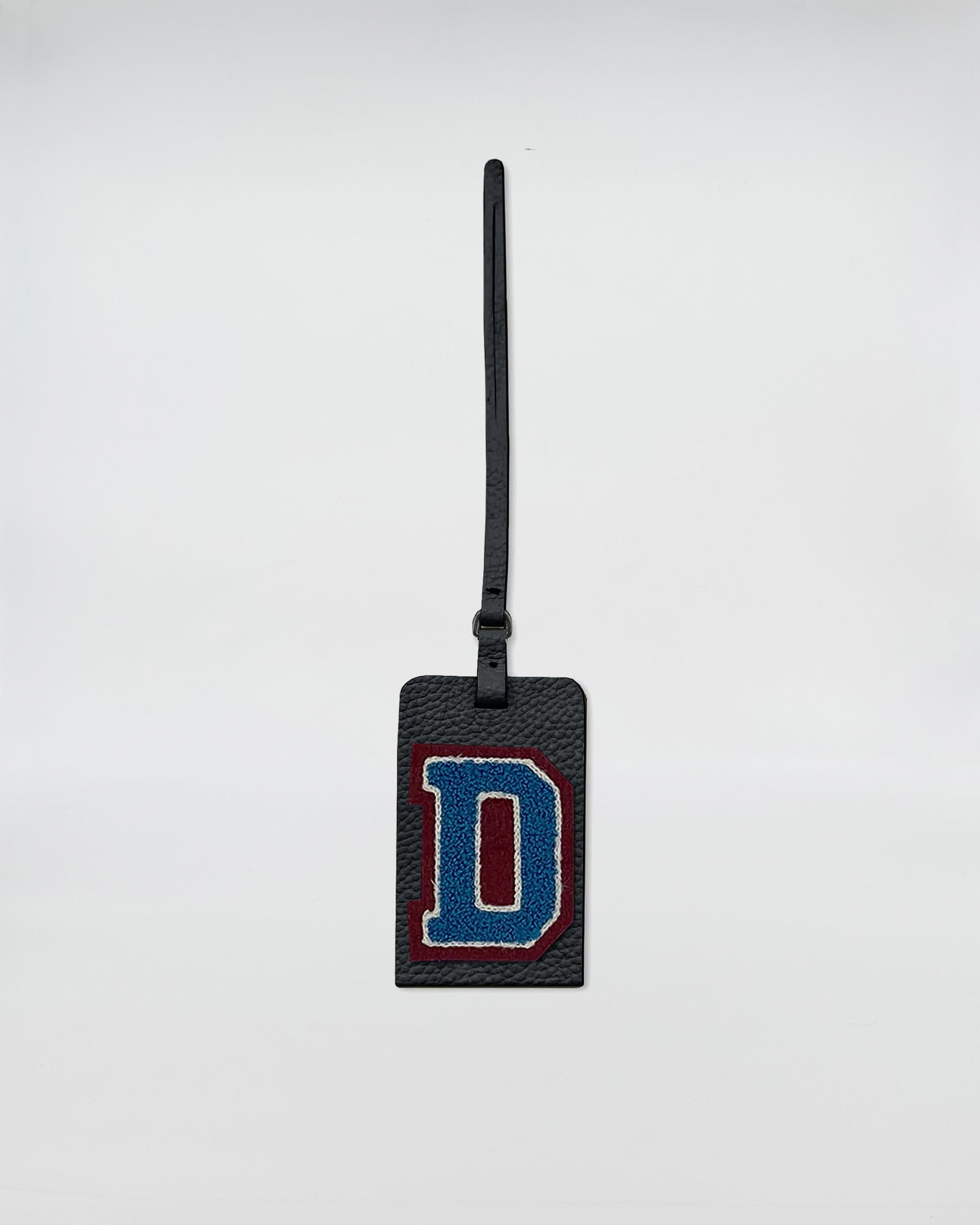 Charm personalizzato patch con lettera D in ricamo su accessorio in pelle rettangolare.