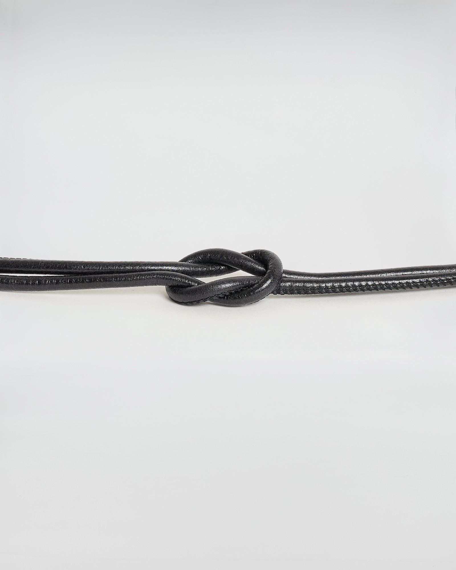 Black leather belt with a unique metal knot design, ideal for adding style to any outfit.