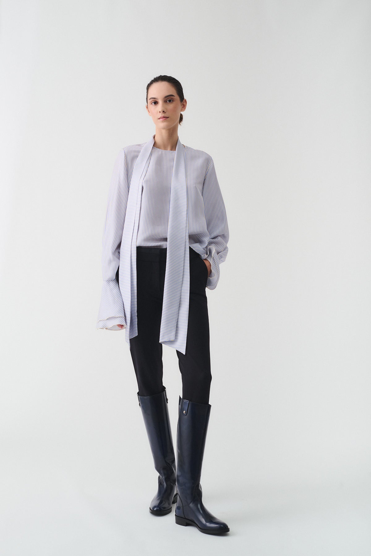 CAMICIA CHARLOTTE IN SETA CON SCIARPA indossata da un modello con stivali alti, elegante e sofisticata.