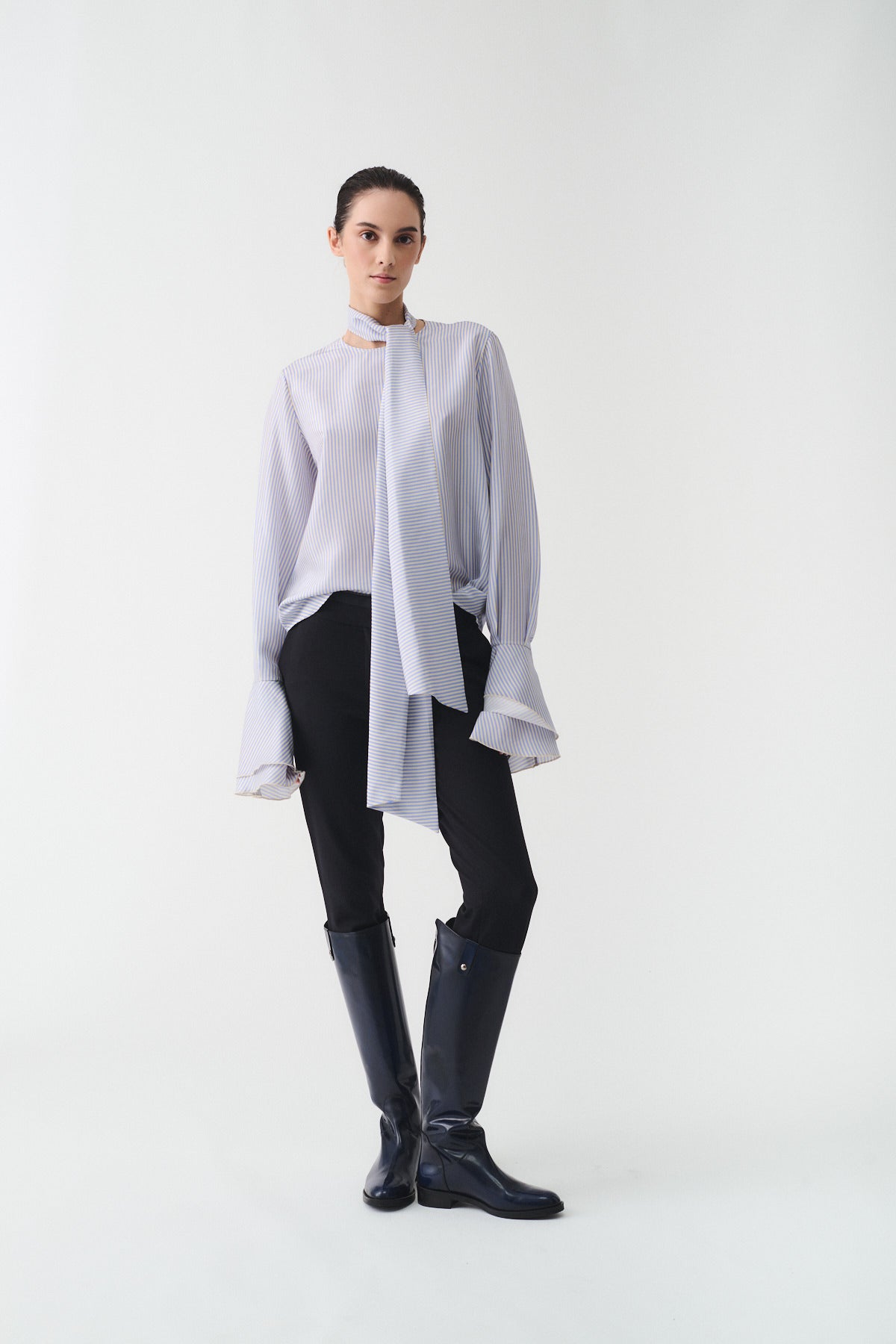 CAMICIA CHARLOTTE IN SETA CON SCIARPA indossata da una donna in abbigliamento elegante, con stivali alti.