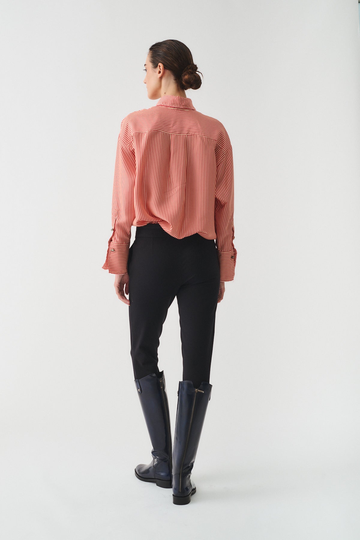 CAMICIA ISOTTA IN SETA CON BOTTONI GIOIELLO worn from the back with black fitted pants and stylish boots.