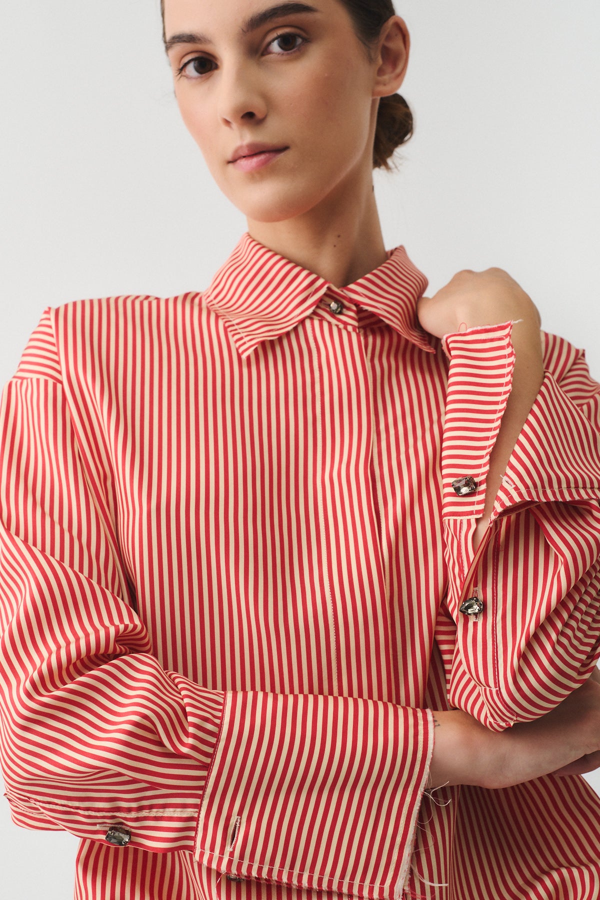 CAMICIA ISOTTA IN SETA CON BOTTONI GIOIELLO indossata da modello, in seta a righe rosse e bianche con dettagli eleganti.