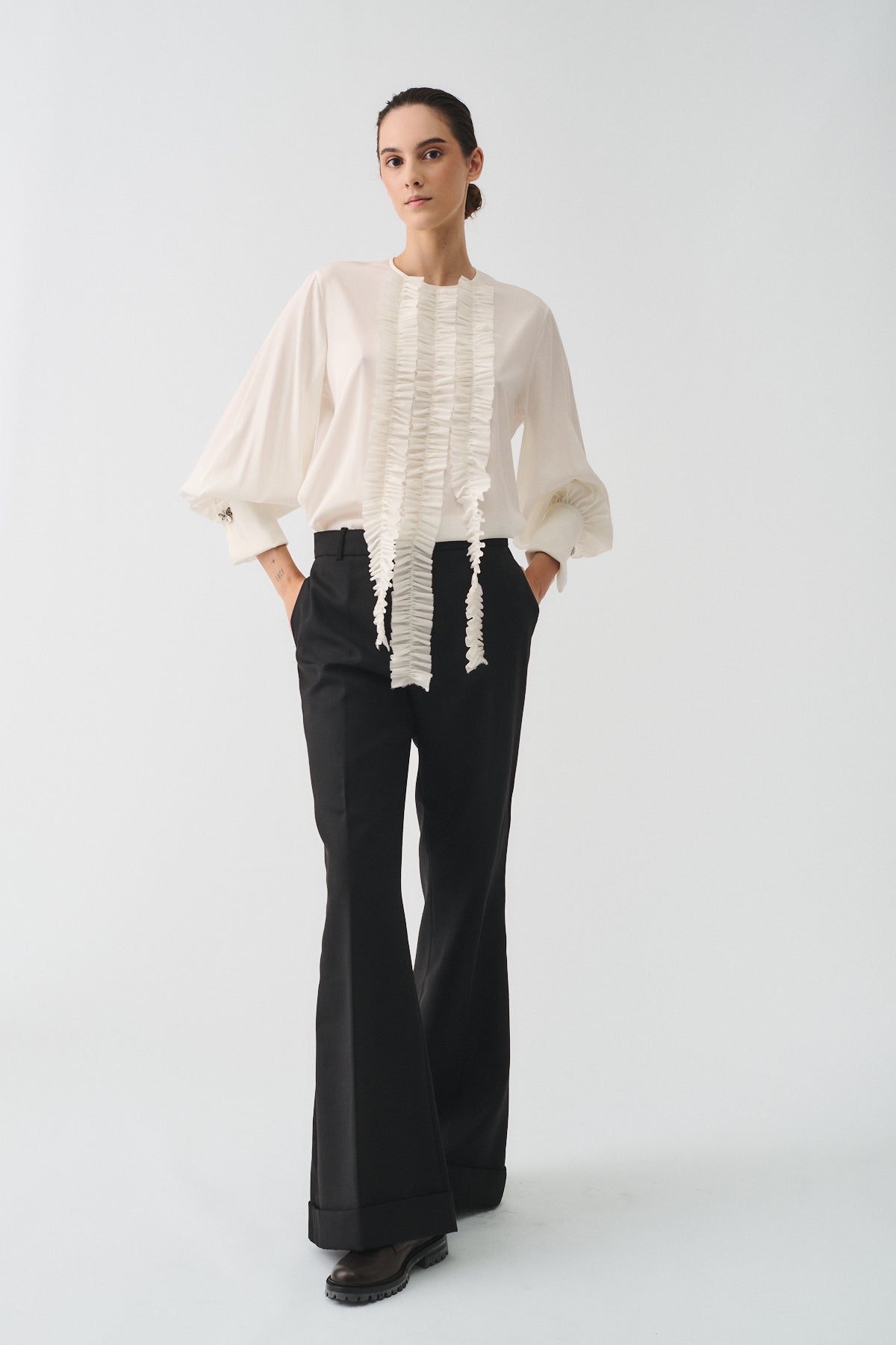 CAMICIA CHARLOTTE IN SETA CON ROUCHES E POLSI CON GEMELLI indossata da una modella in pantaloni neri.
