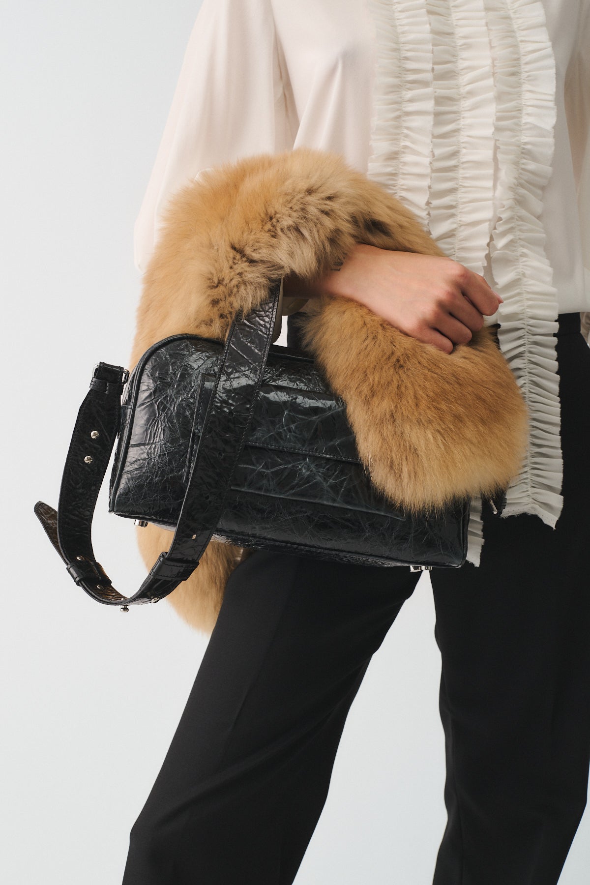 Zoe Small Vitello Strizzato bag with fur detail, stylishly held by a model, showcasing modern design and functionality.