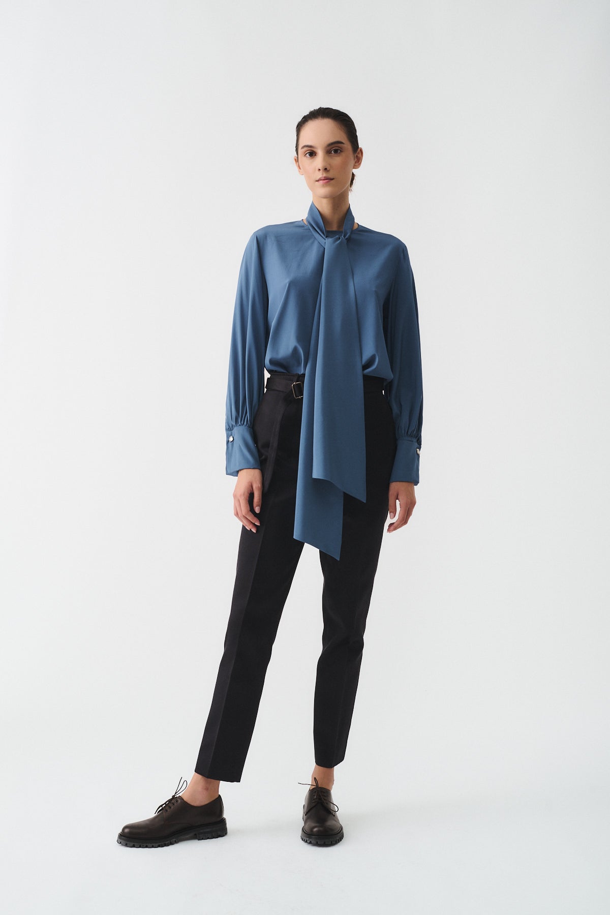 CAMICIA CHARLOTTE IN SETA CON SCIARPA indossata da una donna con pantaloni neri e scarpe eleganti.