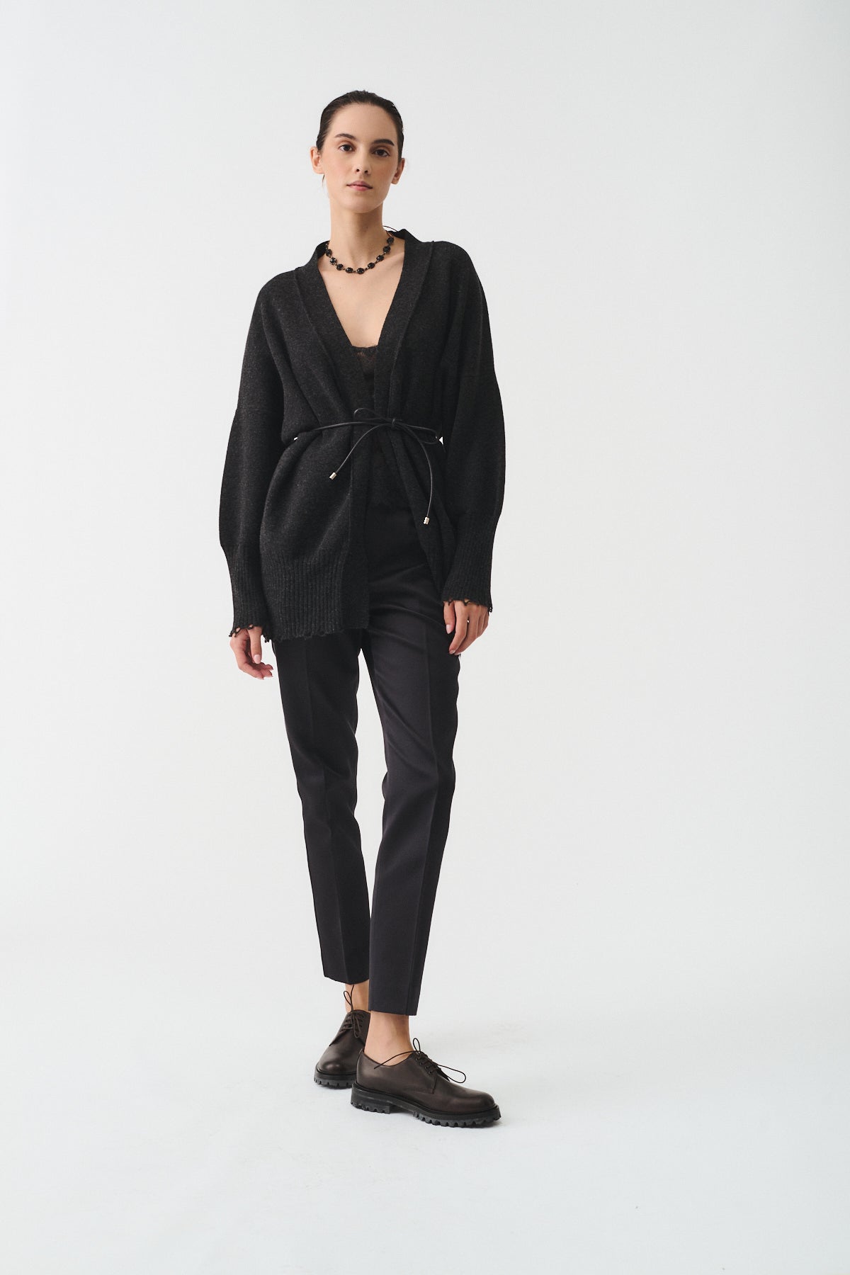 CARDIGAN IN MAGLIA CON CINTURA PELLE worn by a model featuring a stylish black design and elegant accessories.