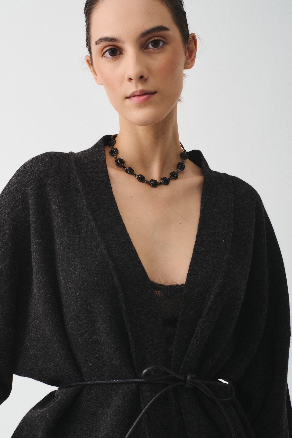 Model wearing a stylish black cardigan with a delicate black crystal floral necklace, showcasing a sophisticated feminine look.