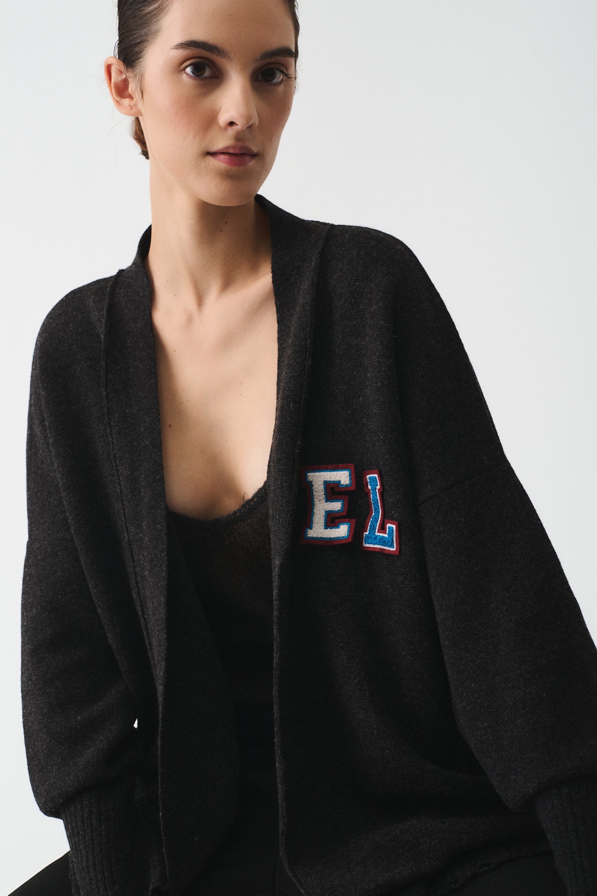 CARDIGAN IN MAGLIA CON CINTURA PELLE PERSONALIZZABILE worn by a model in a stylish black design with charming lettering.