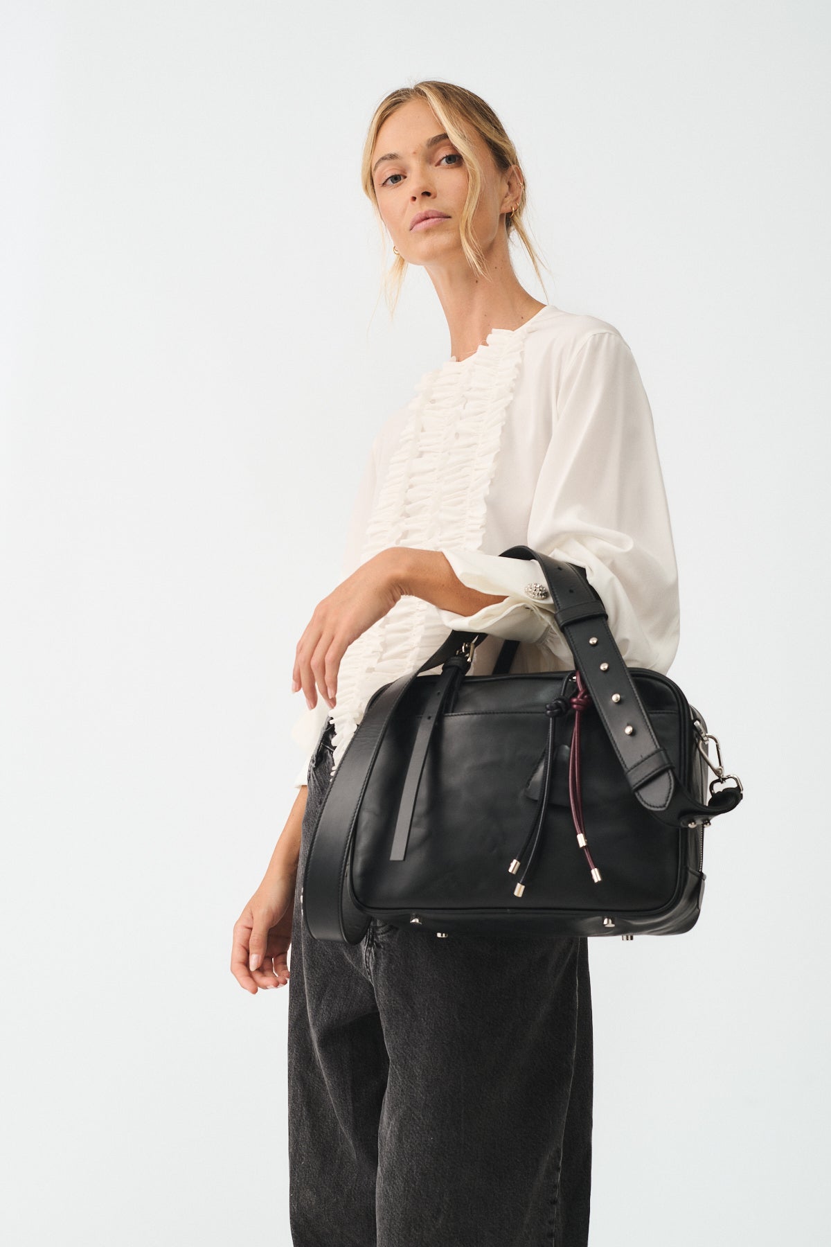 Model wearing FRIDA MEDIUM VITELLO LAVATO bag, showcasing its stylish design and adjustable shoulder strap.