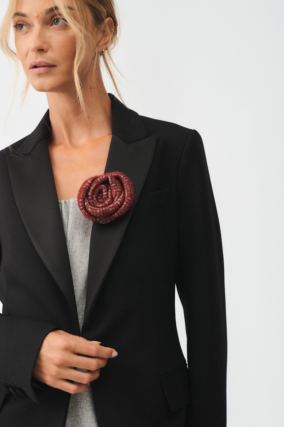 Spilla rosa in lana su giacca nera, un accessorio elegante e contemporaneo per un tocco di stile.