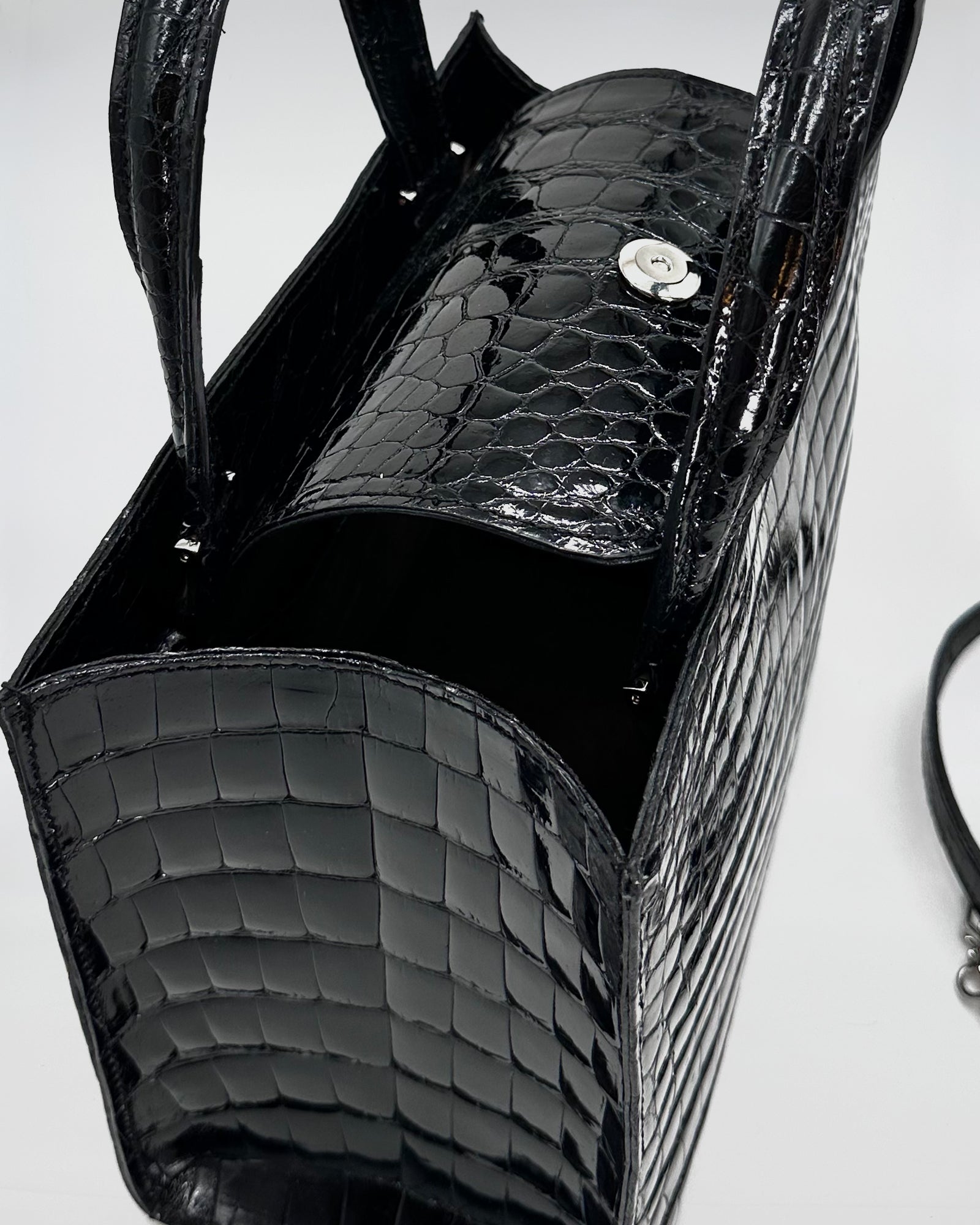 Close-up of the Matilda XS Cocco Recycle handbag in black crocodile-embossed leather with magnetic closure.