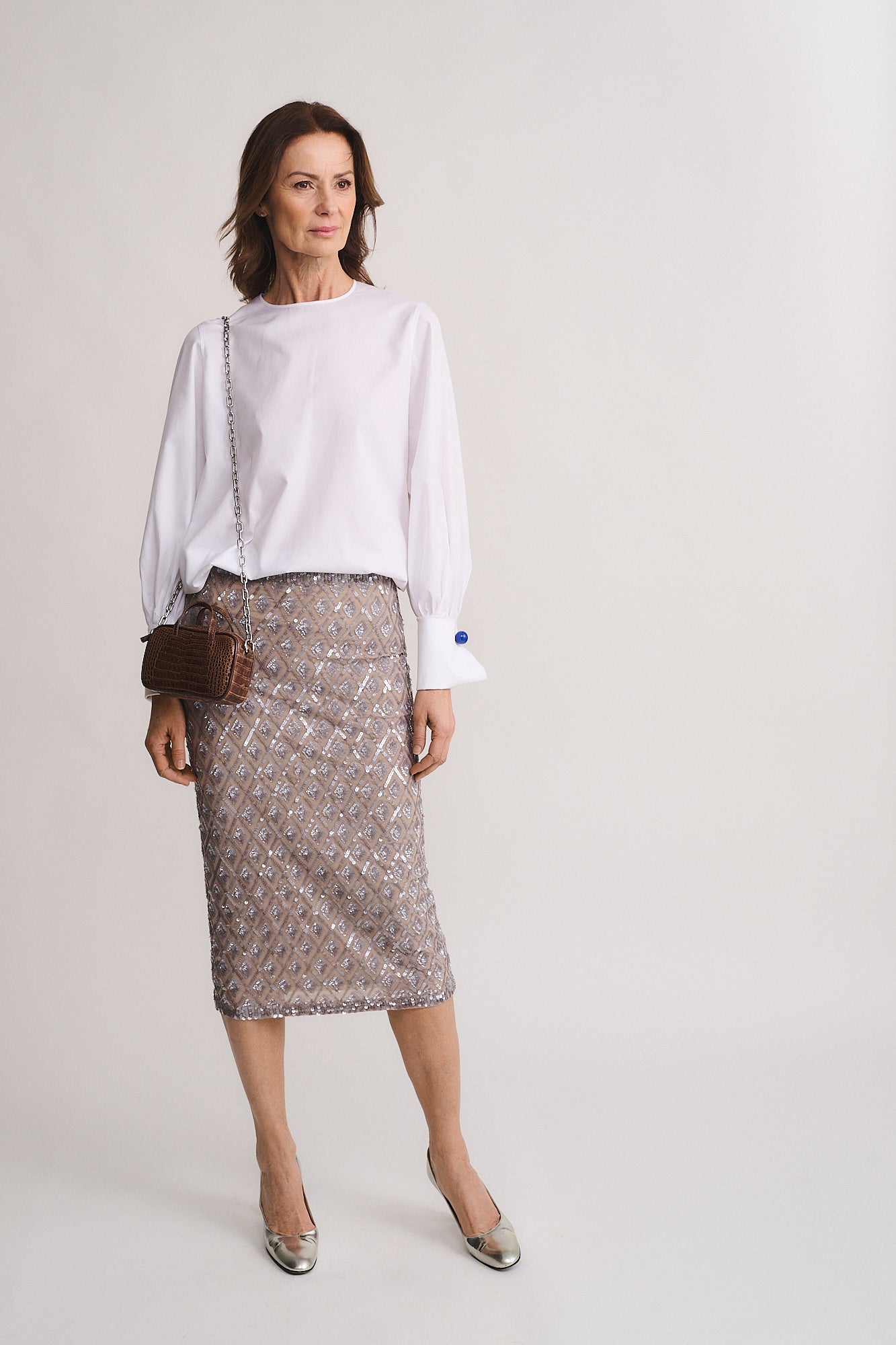 Woman wearing a stylish outfit with a white top, embellished skirt, and micro bag Nina medium cocco recycle.