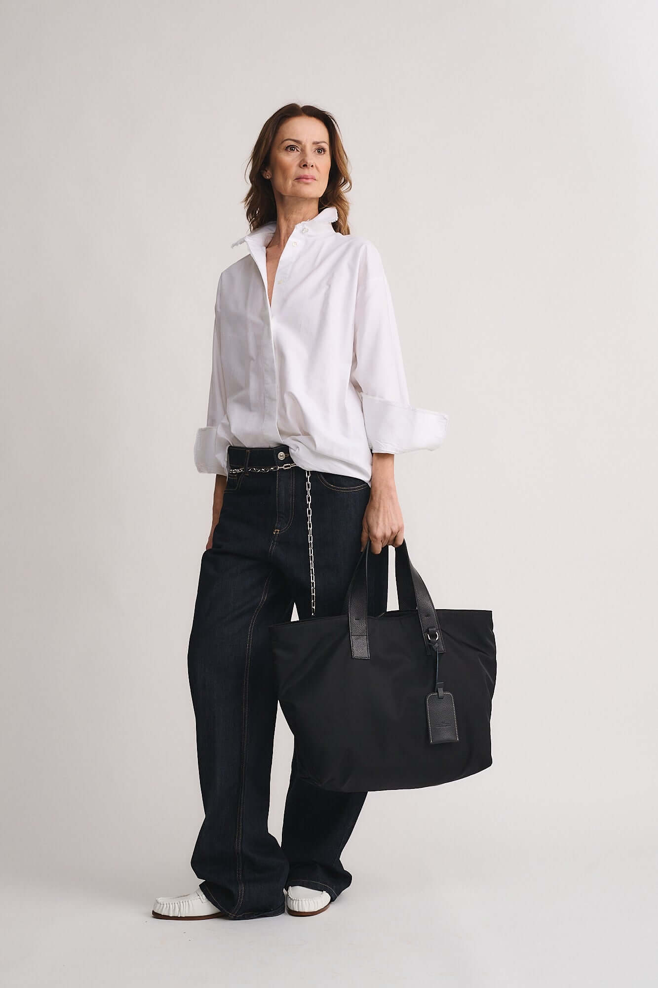Model showcasing the TOMMY RENYLON shopping bag, designed in sustainable Re-Nylon fabric, with leather details in a chic outfit.