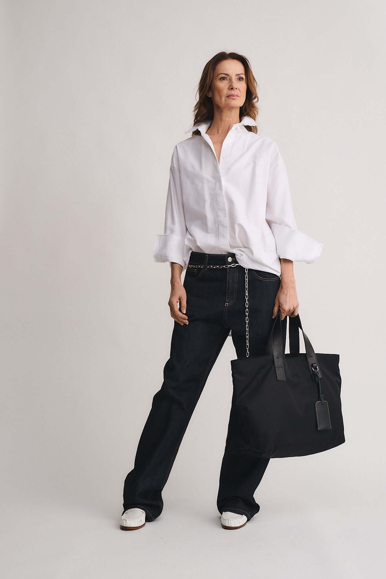 Model wearing a white shirt and black pants, showcasing the TOMMY RENYLON shopping bag.
