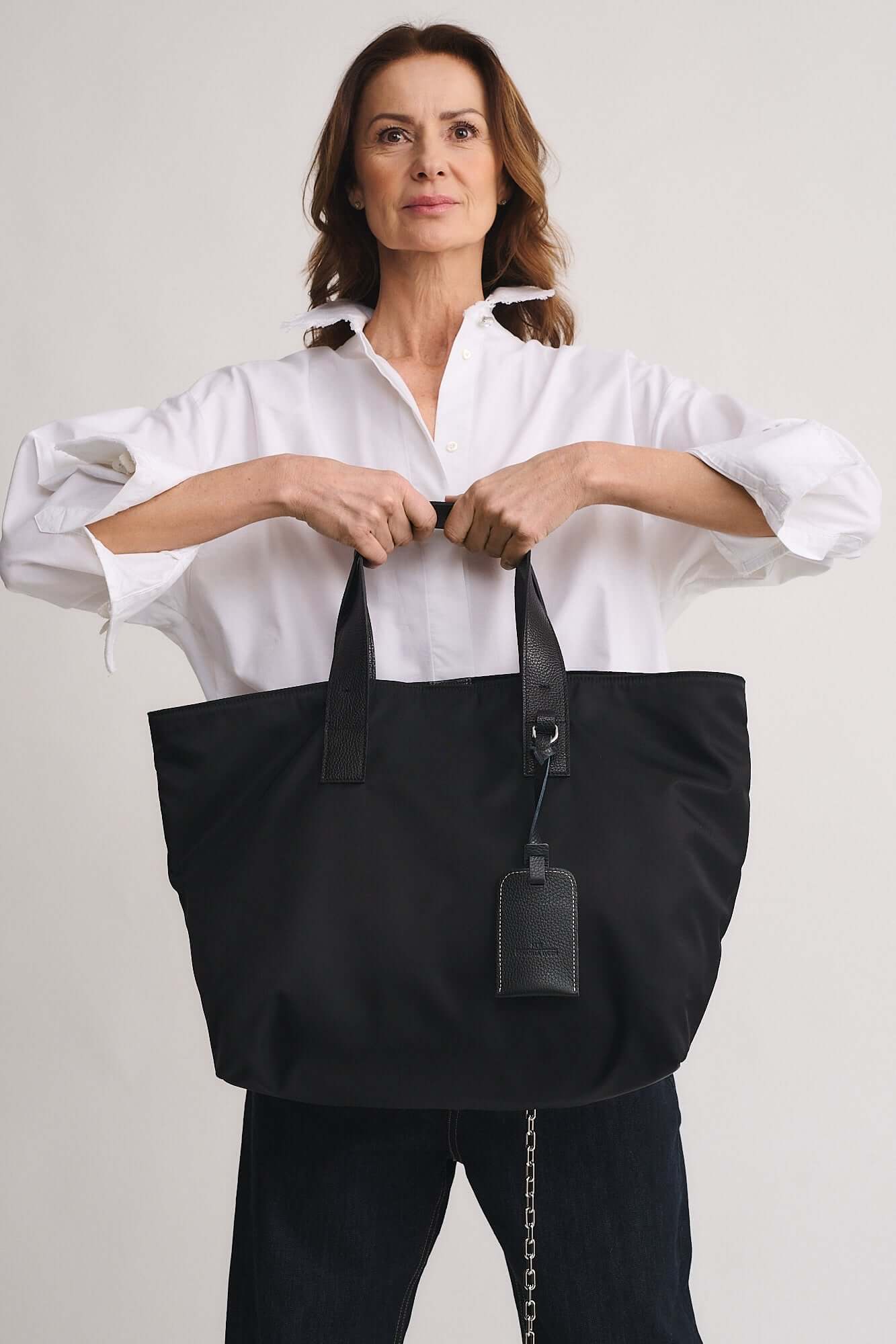 Model showcasing TOMMY RENYLON shopping bag, featuring Re-Nylon fabric and leather details for a modern, elegant look.