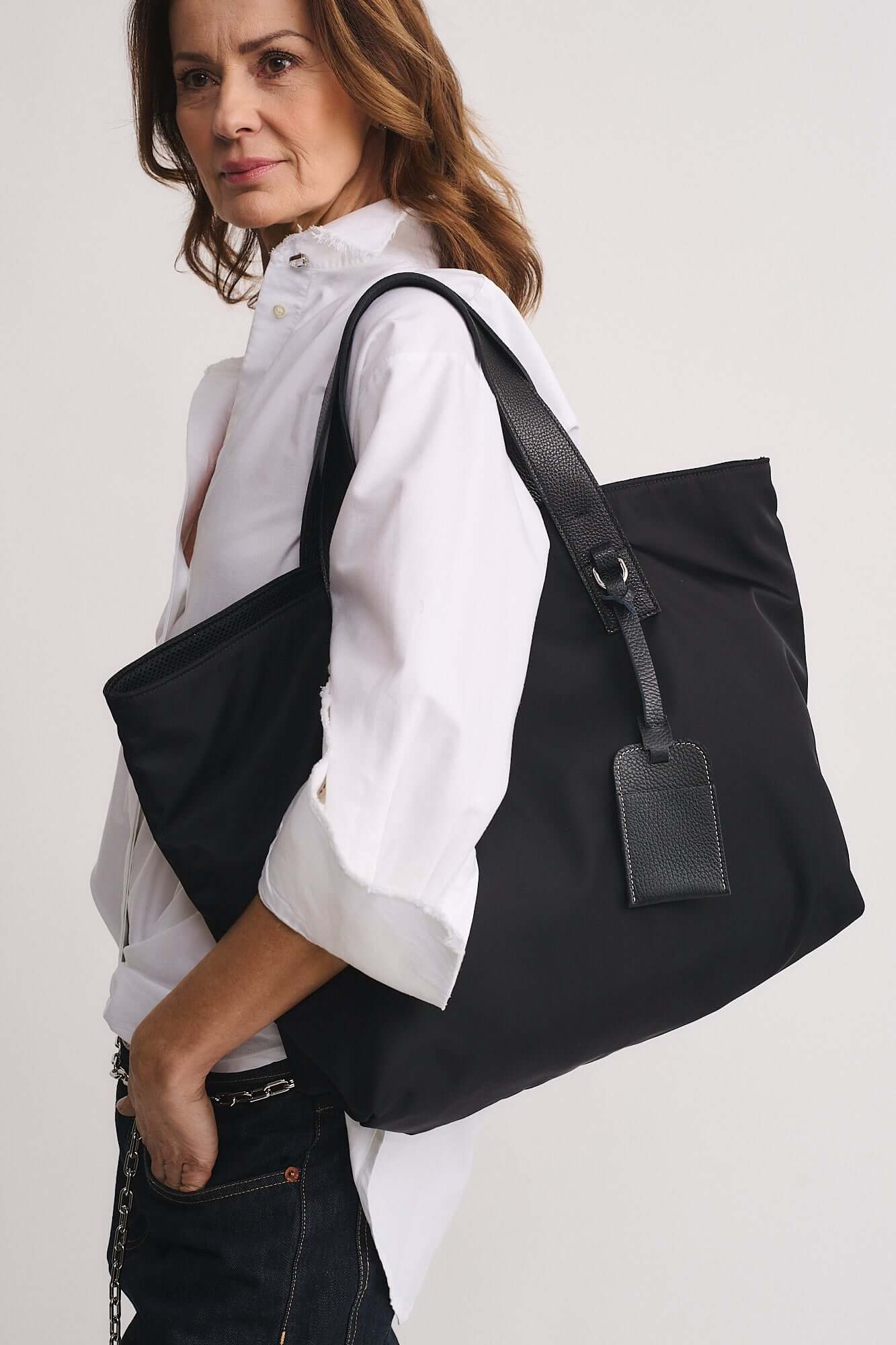 Model showcasing TOMMY RENYLON shopping bag made of sustainable Re-Nylon fabric with leather details.
