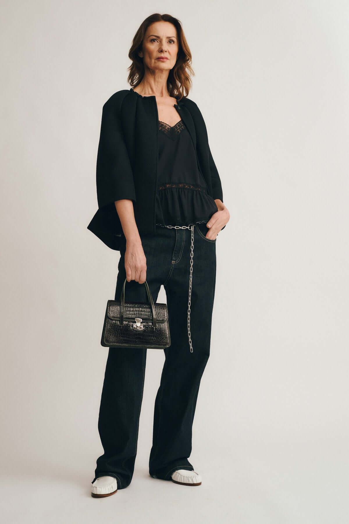 Model wearing stylish black outfit with a handbag, showcasing elegance and modern fashion for OFELIA COCCO RECYCLE EDITION.