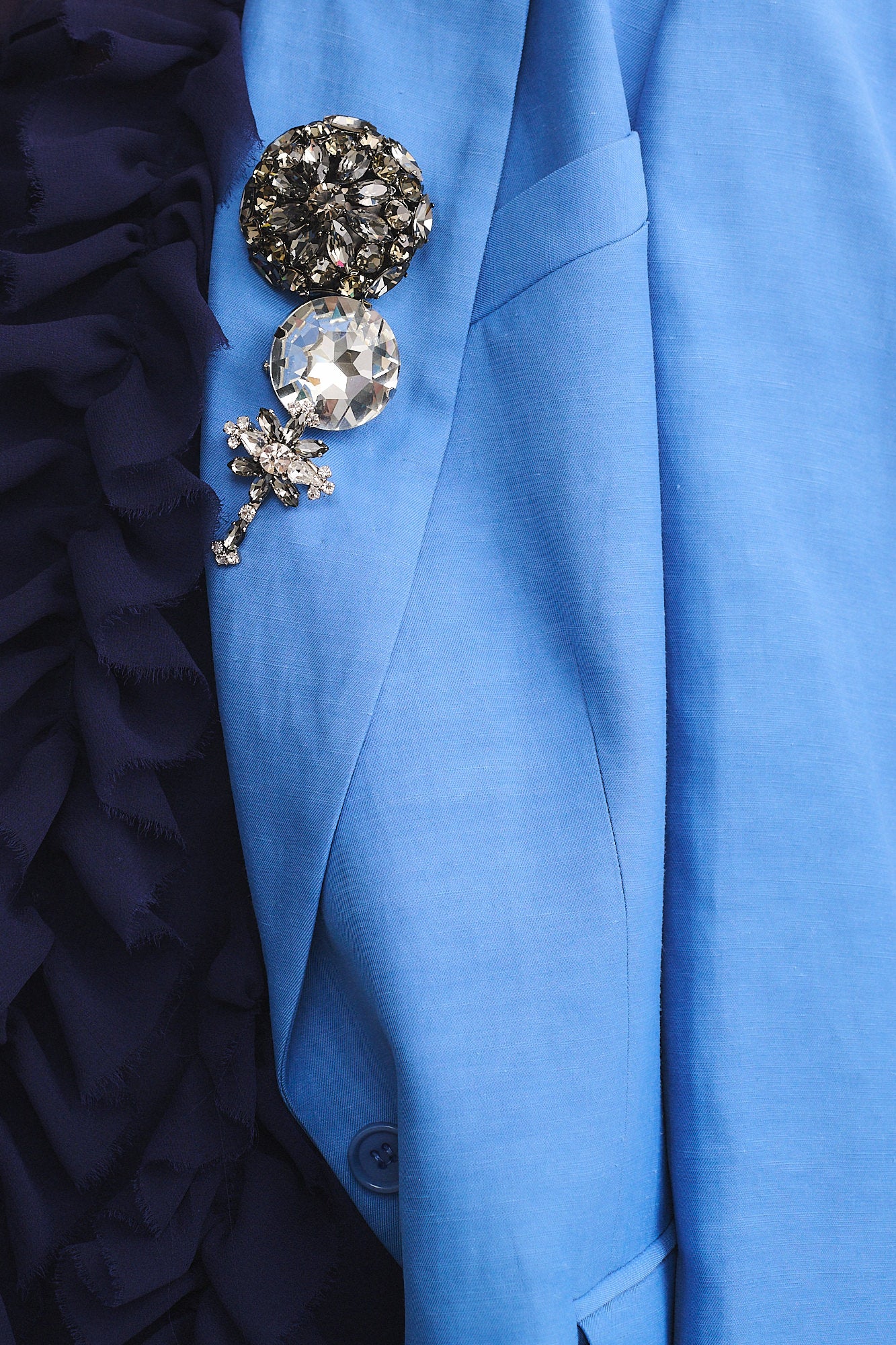 SPILLA IN STRASS con cristalli decorativi su giacca blu elegante, aggiungendo un tocco vintage e scintillante.