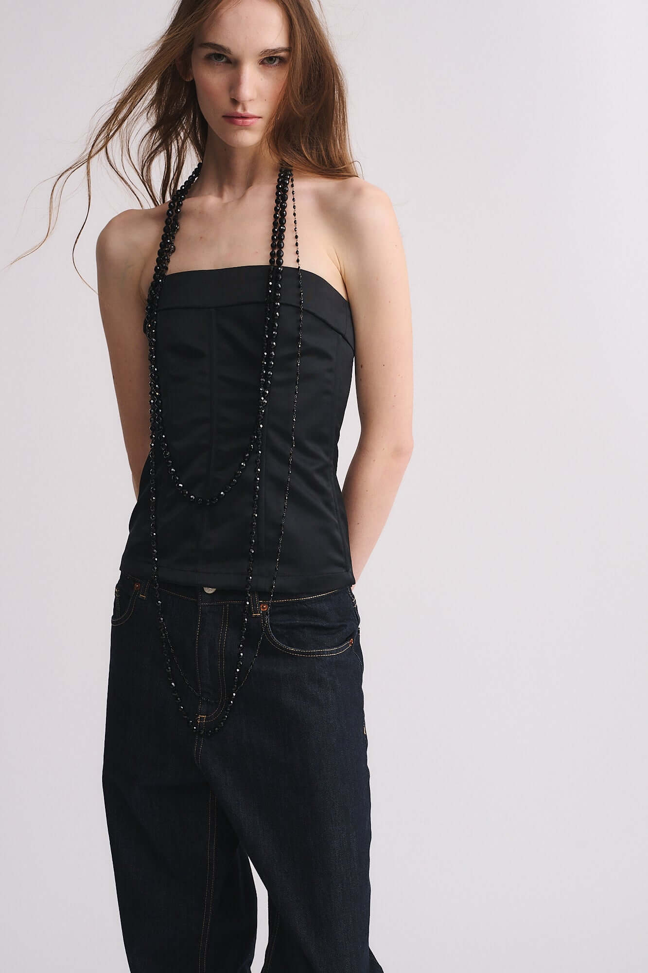 Model wearing COLLANA MOD. 48, a necklace of half crystal beads, styled elegantly with a black top and jeans.