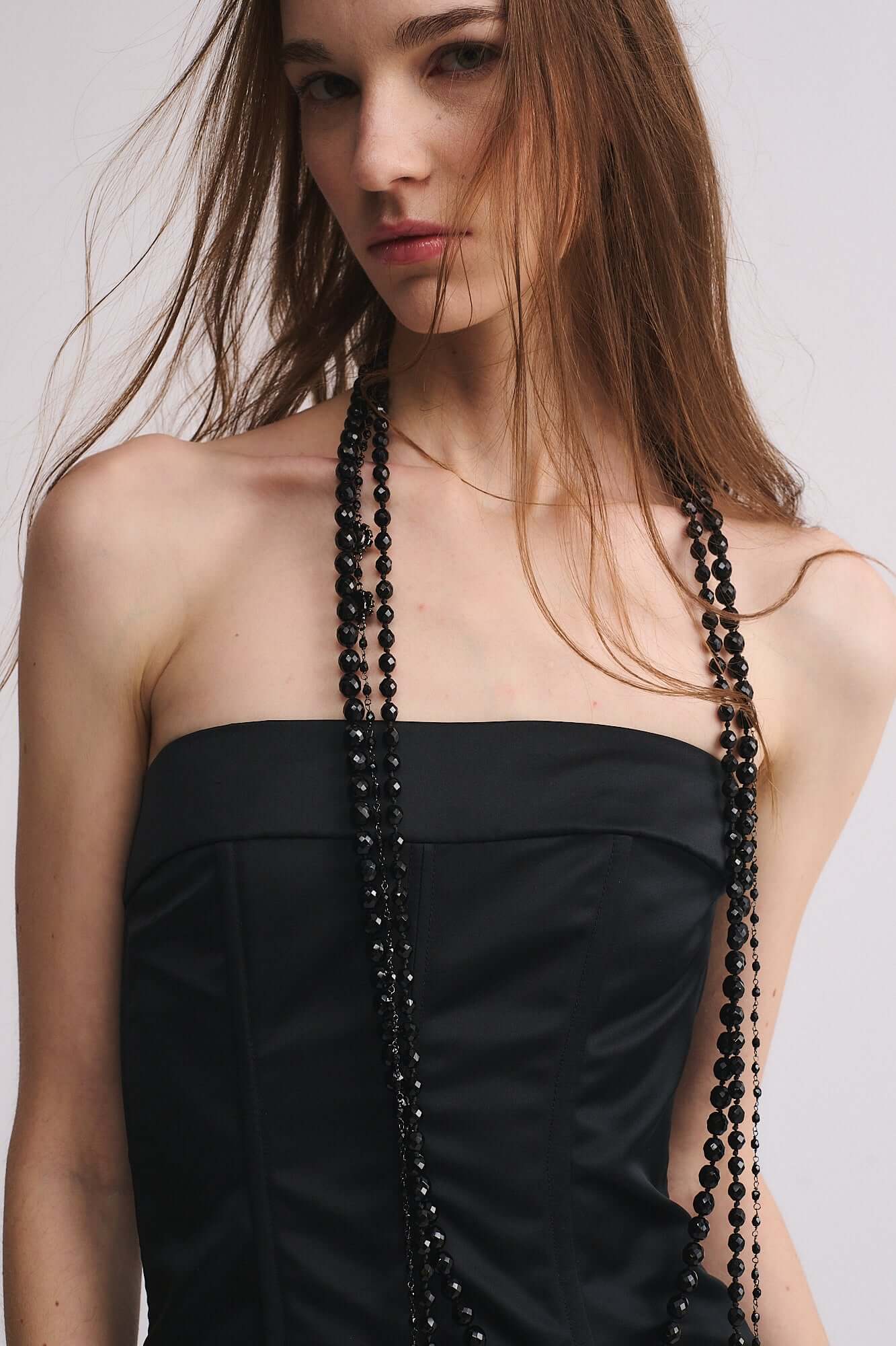 Collana Mod. 48 indossata da una modella con abito nero, elegantemente drappeggiata con perle di mezzo cristallo.