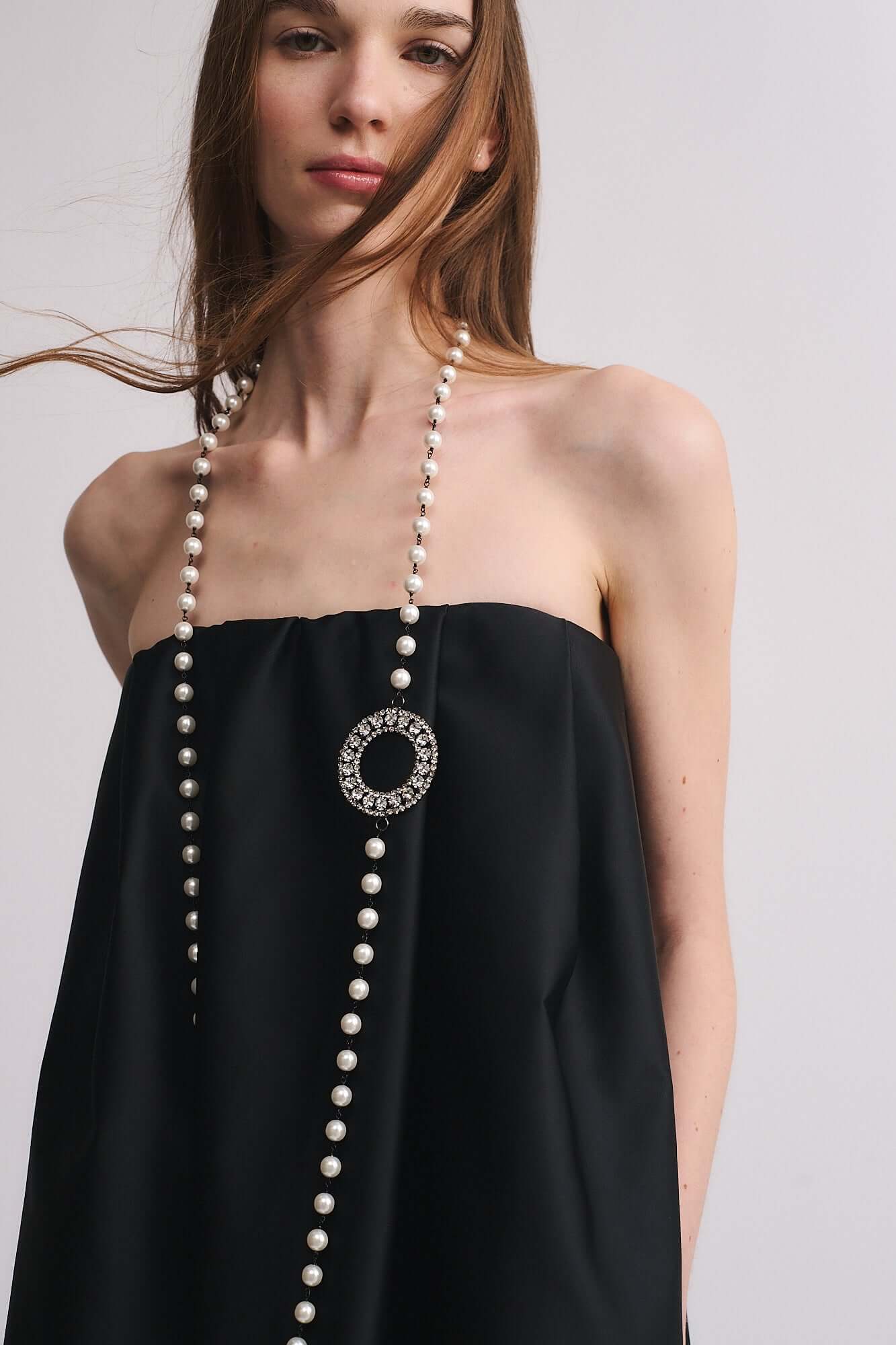 Collana Mod. 39 indossata da una donna, composta da perle ed accessorio in strass color cristallo.