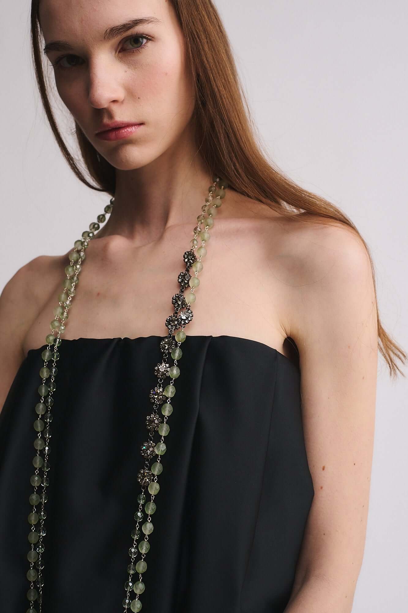Modella indossa COLLANA MOD. 47 con perle e accessorio in strass, abbinata a un top nero.