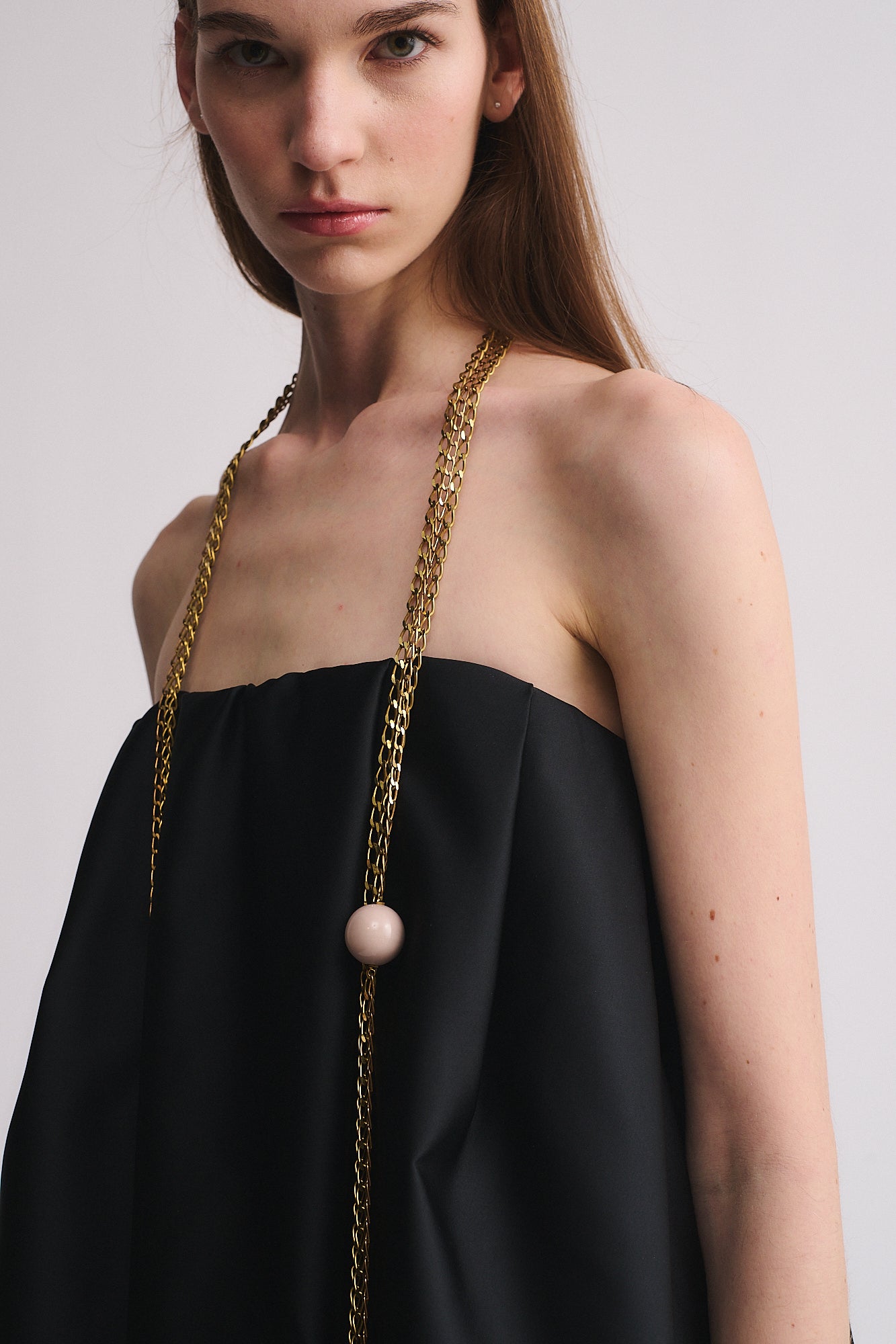 Moderna COLLANA MOD. 32 indossata con top nero, caratterizzata da catene in ottone e boule in resina, elegante e contemporanea.