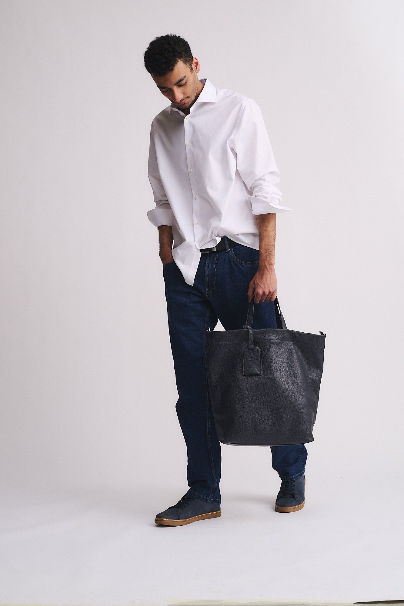 Uomo con borsa Ford in pelle, camicia bianca e jeans, mostrando eleganza e funzionalità.