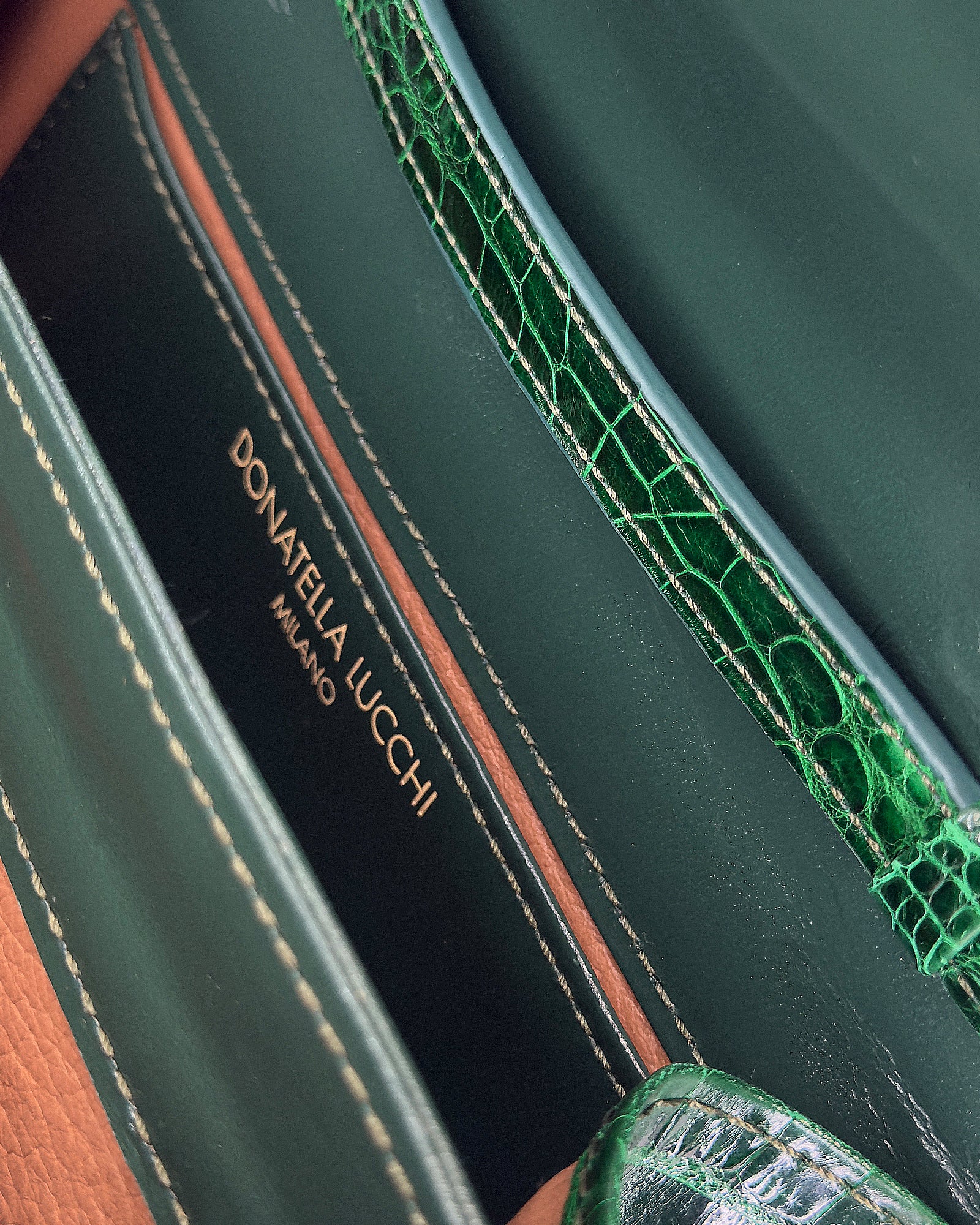 Close-up of a luxury green leather handbag interior featuring Donatella Lucchi branding and textured accents.