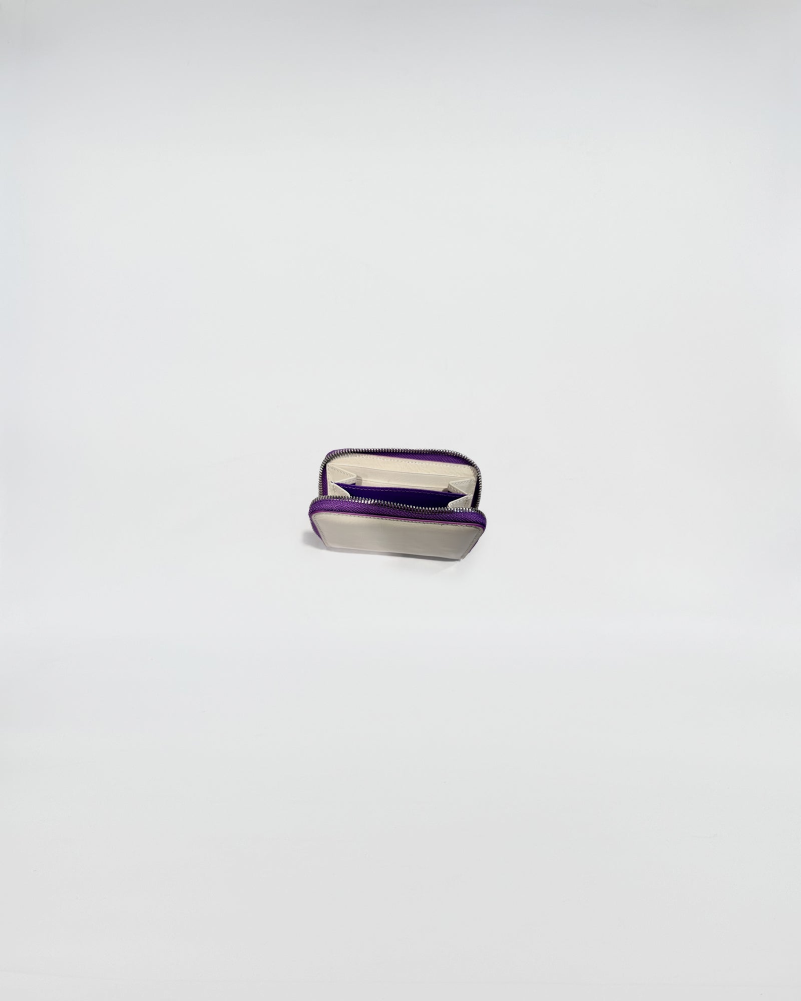 Portafoglio Zip Mini aperto, mostra interni in pelle e chiusura con zip viola, design sofisticato.