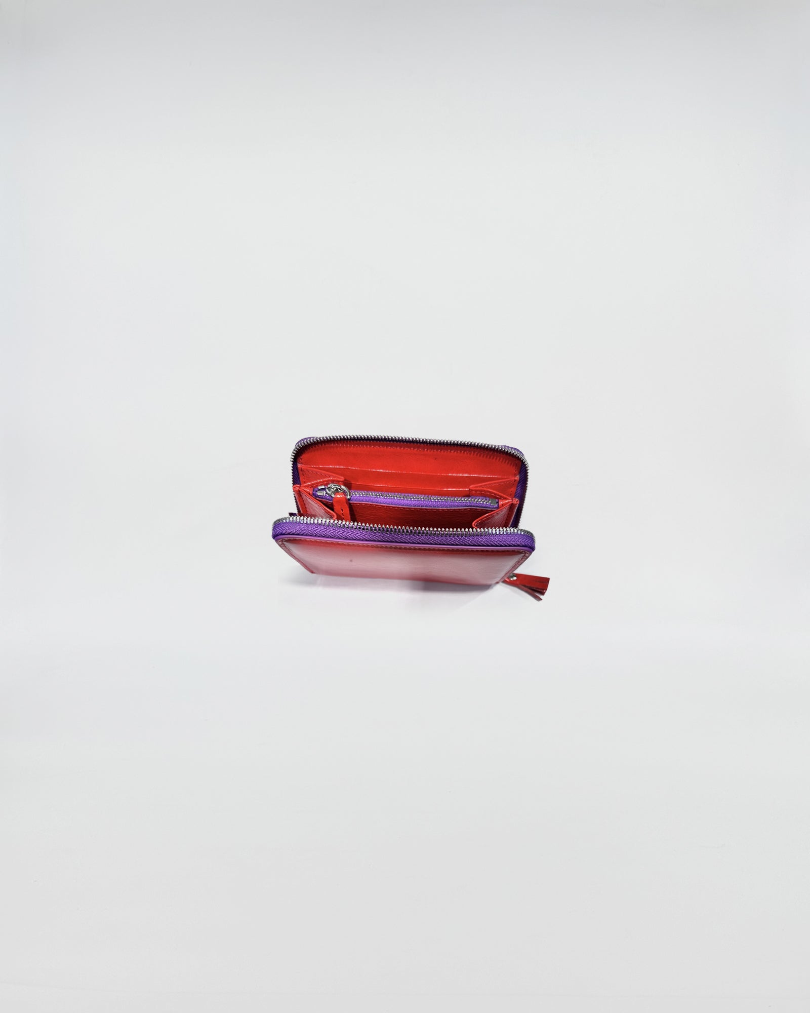 Portafoglio Zip Small aperto con interni rossi e viola, ideale per riporre carte e monete.