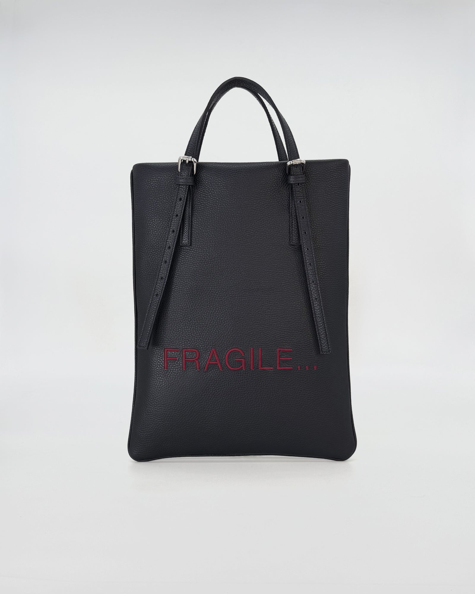 Elegant black leather bag with the word 'FRAGILE' in red, perfect for modern work and stylish outings.