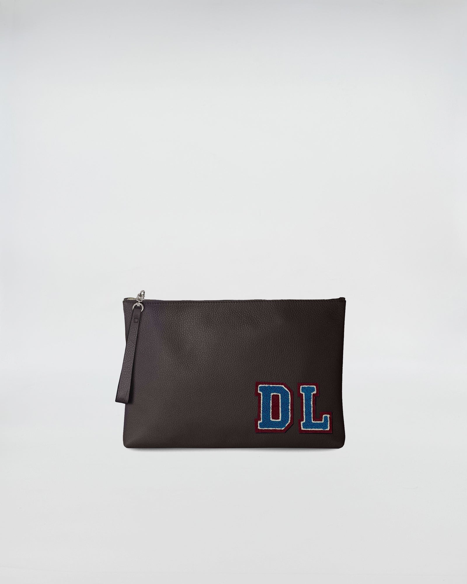 BUSTA A4 PERSONALIZZATA in pelle scura con patch DL, chiusura con zip e manicotto per portarla a mano.