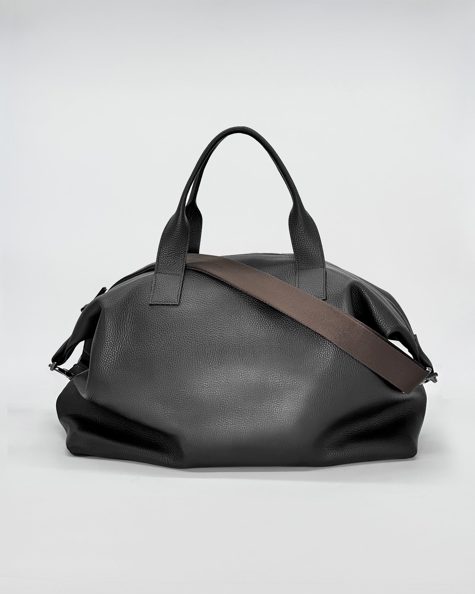 Black travel bag with a removable brown shoulder strap and sturdy handles, ideal for weekend getaways.