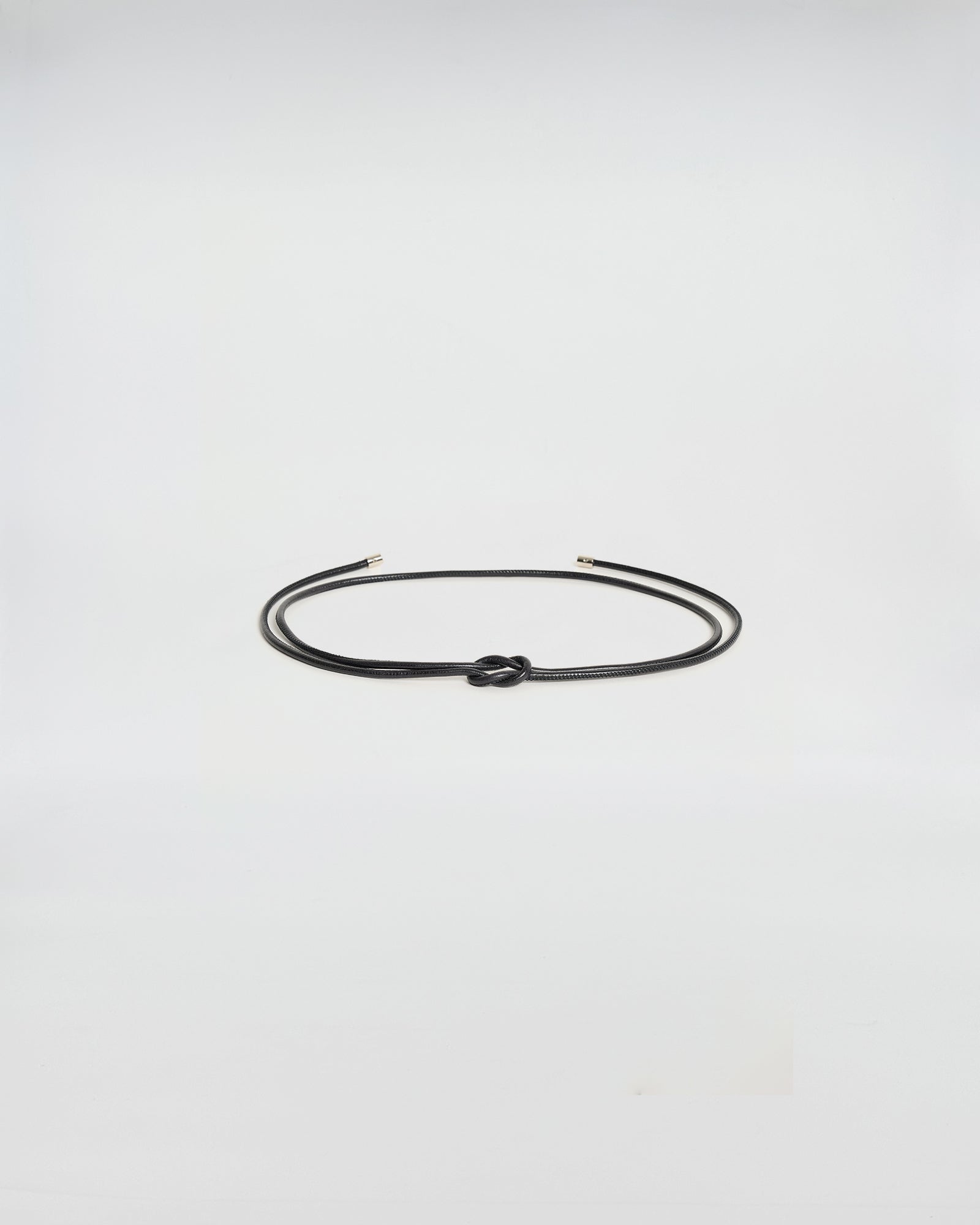 Cintura tubolare in pelle nera con terminale metallico, ideale per aggiungere stile e definire la vita.