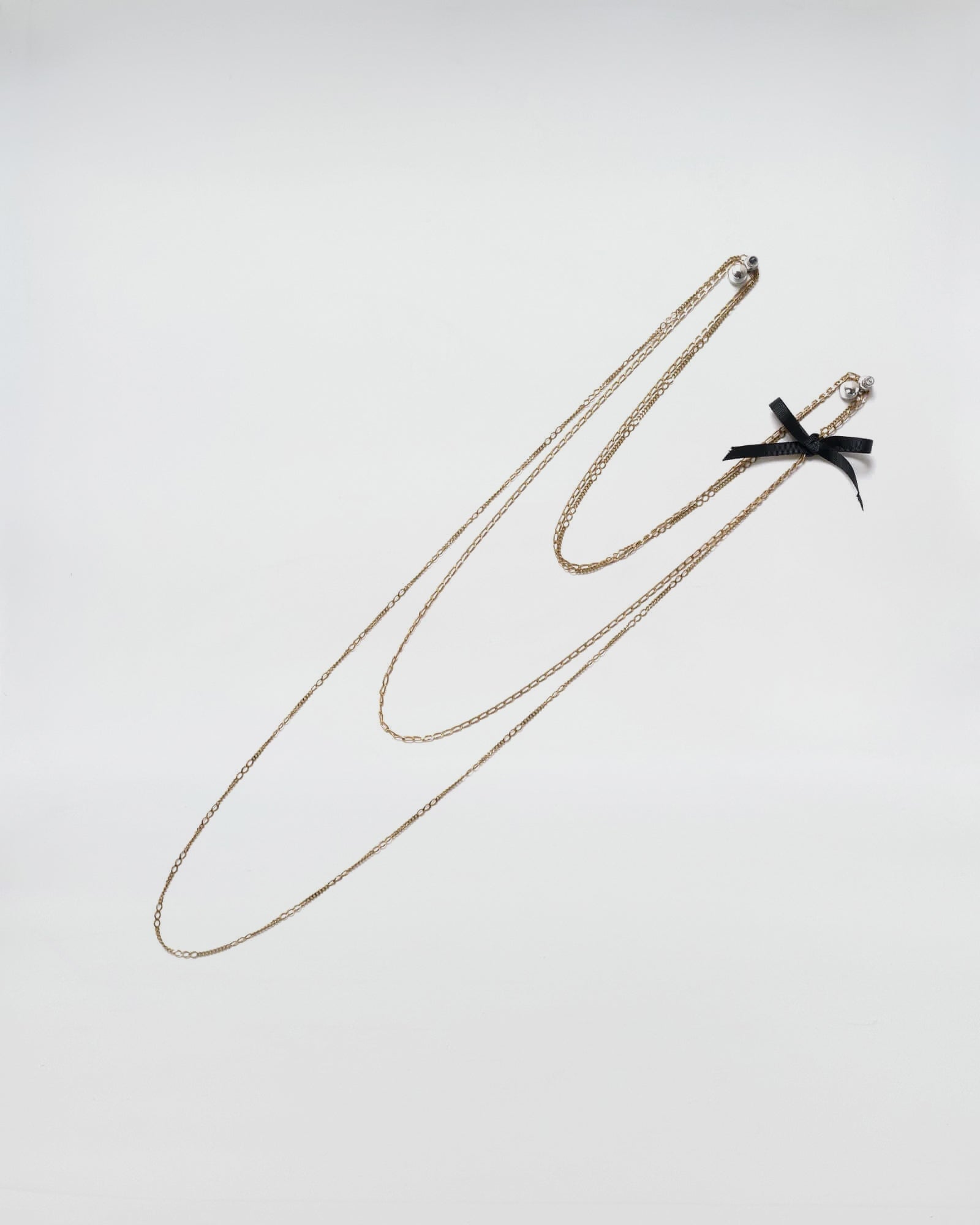 Collana Mod. 31, elegante necklace with brass chains and a black bow, inspired by 1930s fashion with a modern twist.