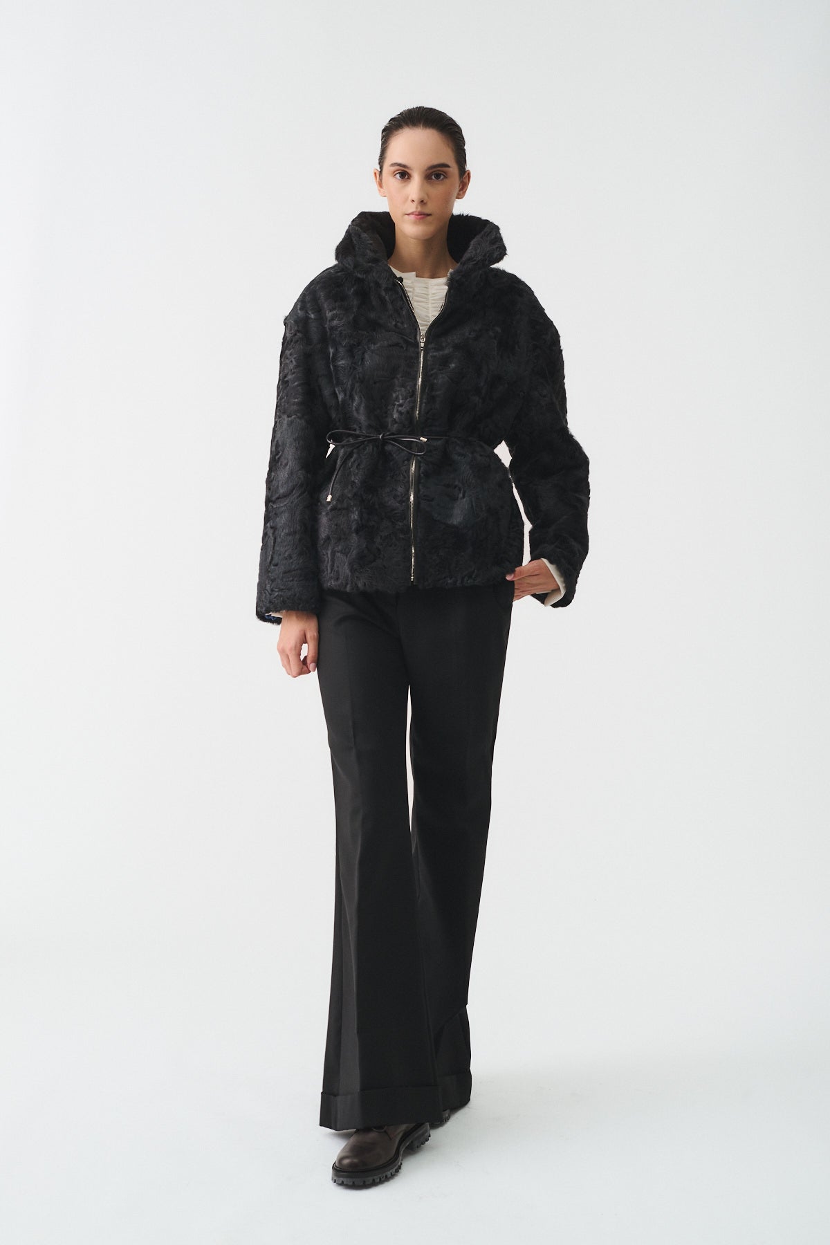 Model wearing the BLOUSON ASTRAKAN UPCYCLE, a black textured jacket with a belted waist and sophisticated style.