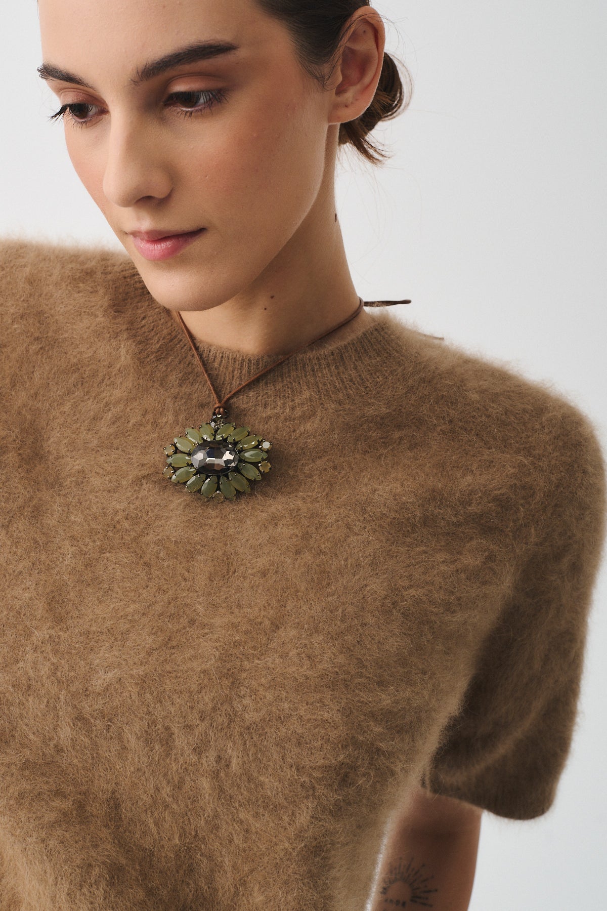 Collana Dori con maxi ciondolo di cristallo indossata da una donna in maglione beige.