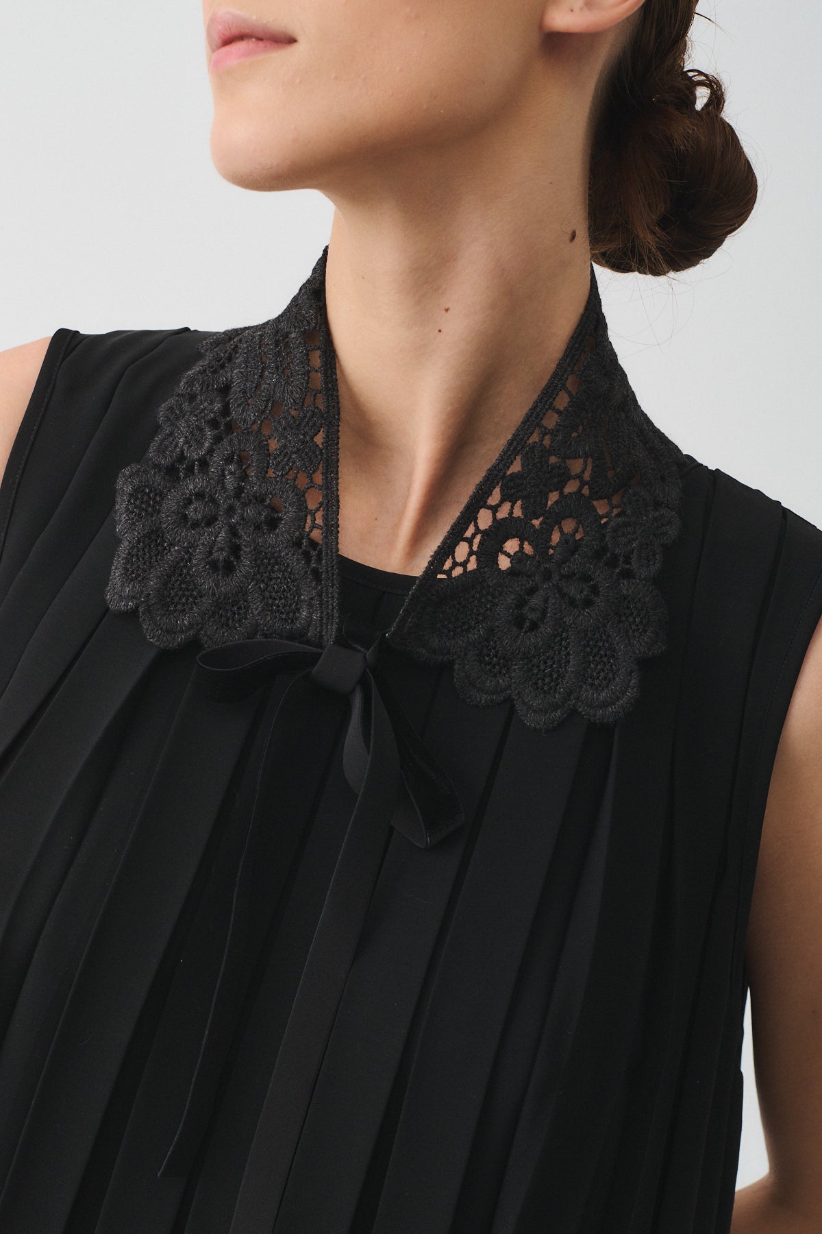 Elegant black macramé lace collar with floral design, adding a romantic touch to a chic outfit.