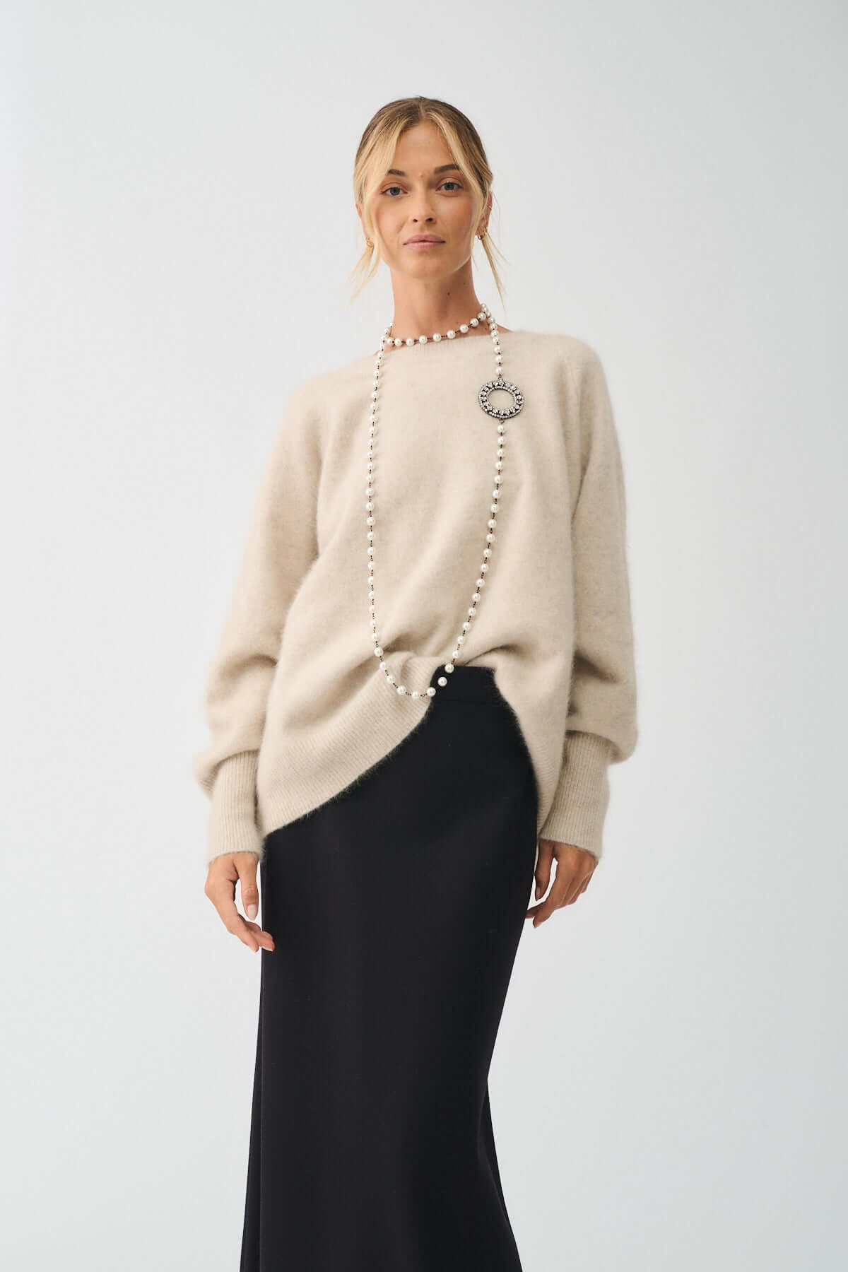 Modella che indossa la COLLANA MOD. 39 con perle e strass, abbinata a un maglione e gonna elegante.