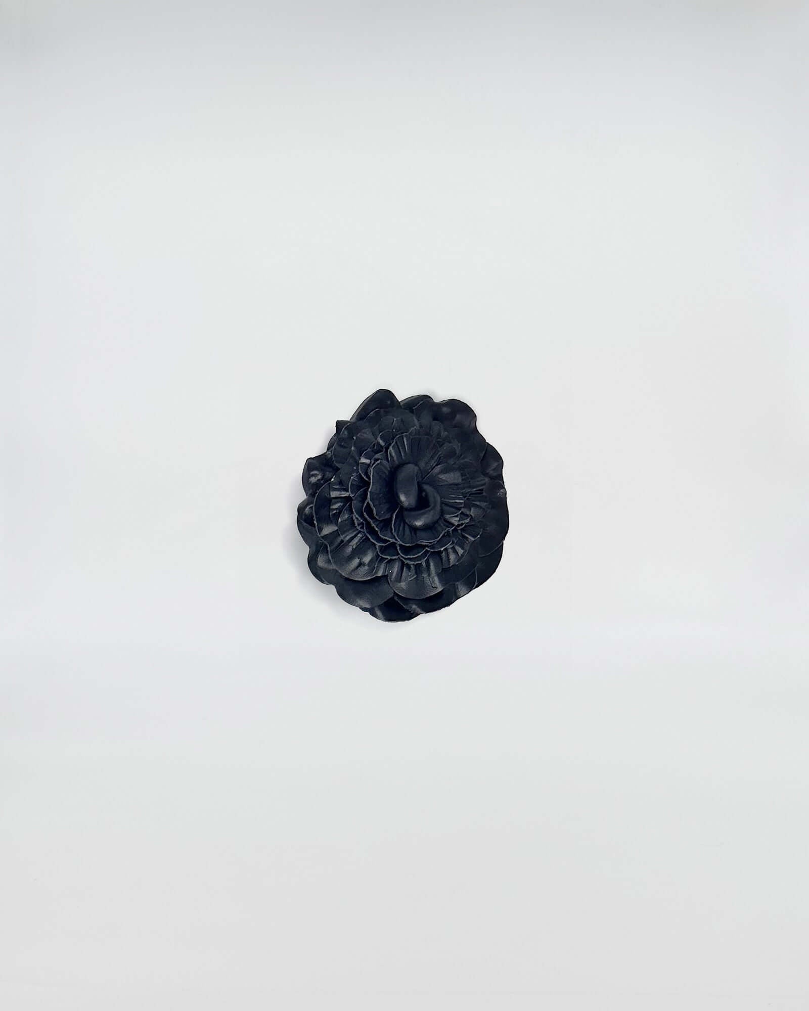 Spilla rosa in pelle nera, elegante accessorio artigianale per abbigliamento e borse.