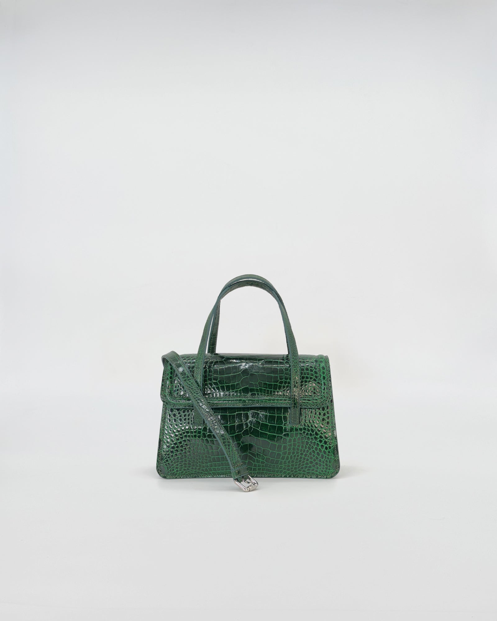 Elegant green crocodile-patterned handbag with structured design and dual handles.