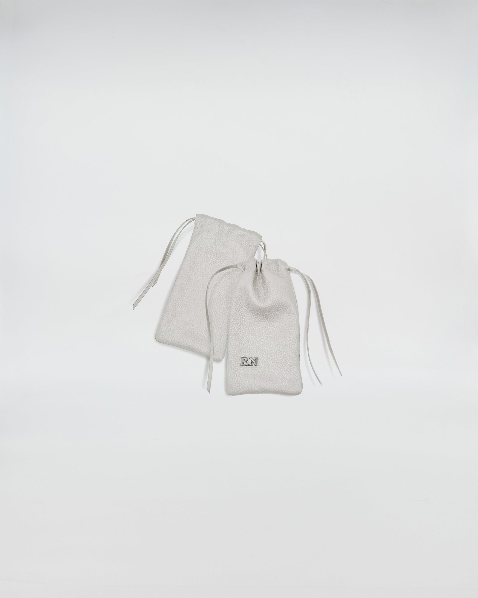 PORTA OCCHIALI LEO - Set of two white fabric pouches with drawstrings for eyewear storage.