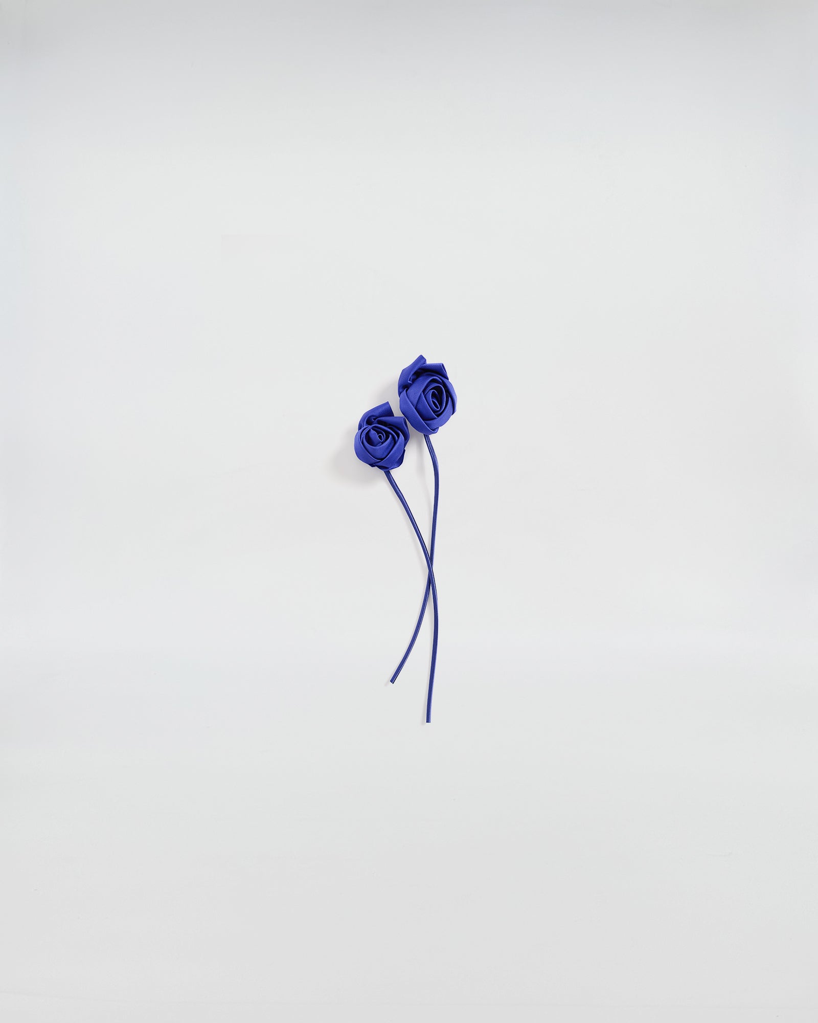 Boccioli di rosa in raso blu, accessorio elegante per giacche e abiti, design artigianale e romantico.