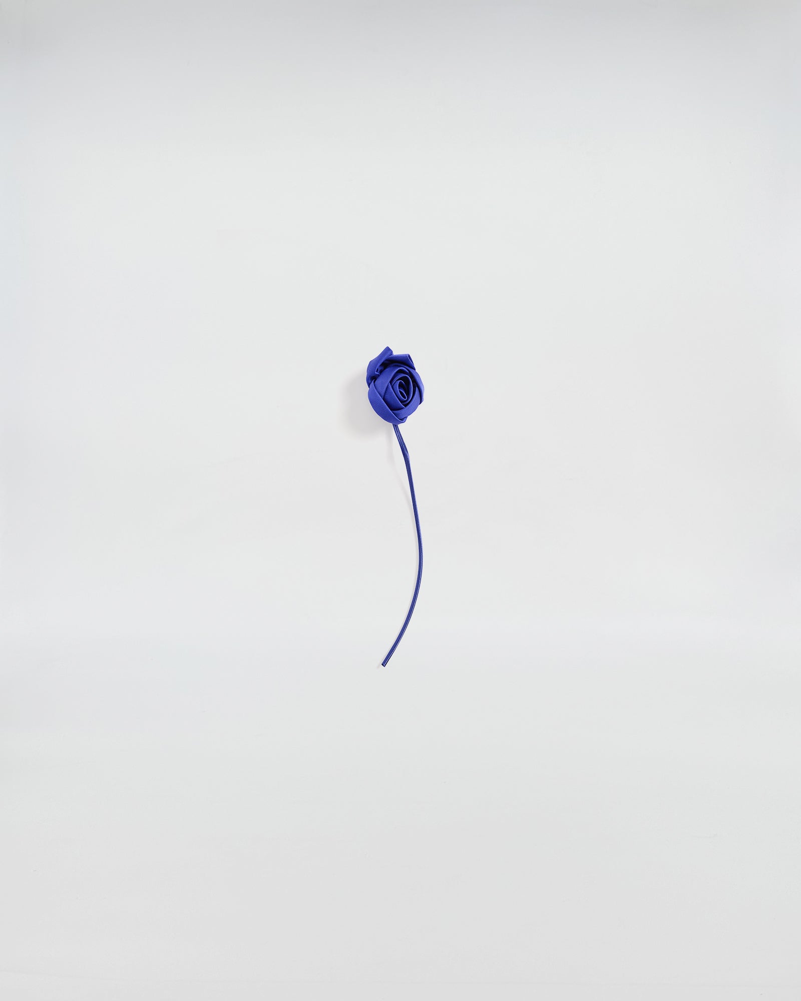 Elegante spilla con bocciolo di rosa in raso blu, dettaglio artigianale per accessori distintivi.