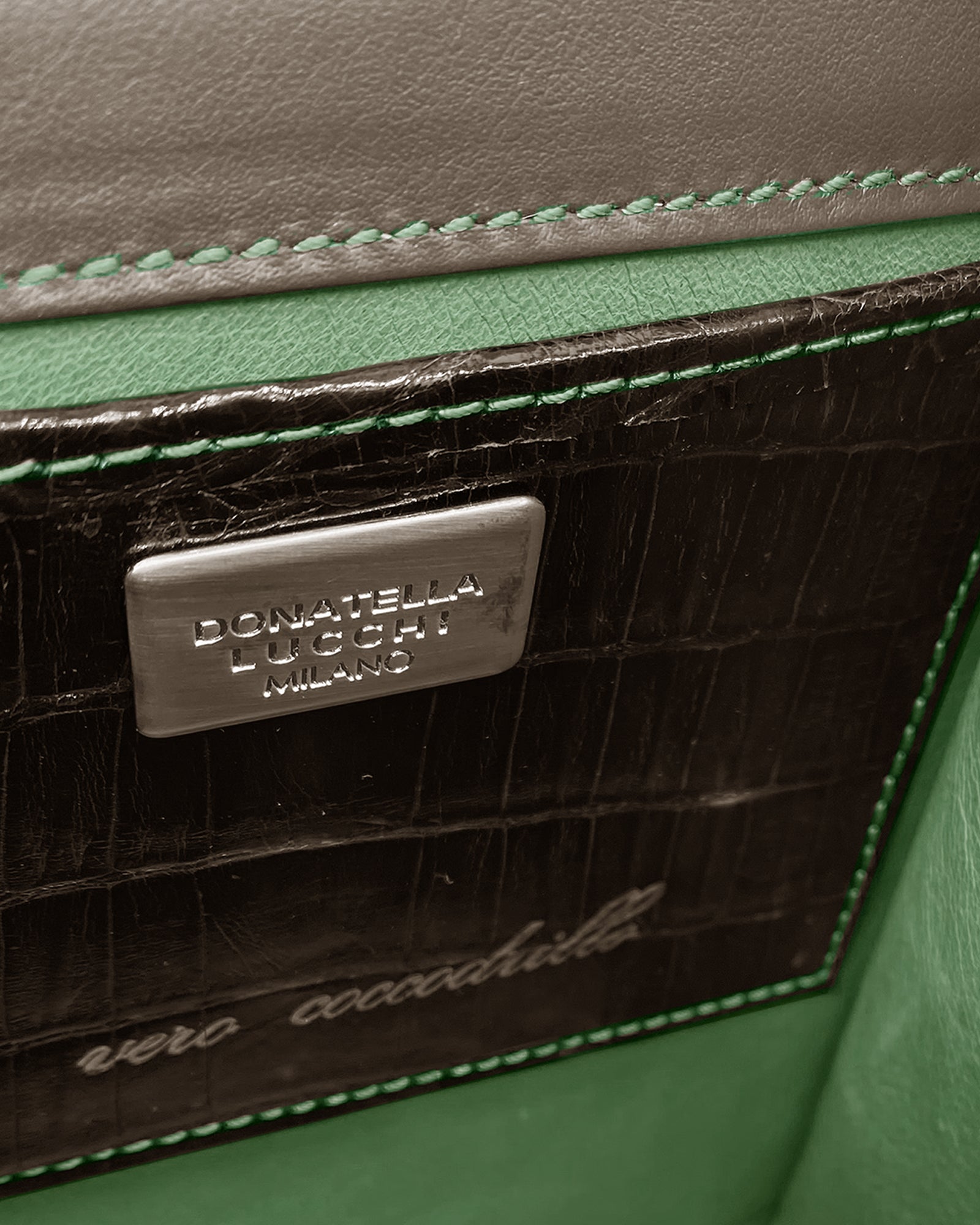 Close-up of the SISSI - COCCO RECYCLE bag's interior showcasing green suede and unique crocodile leather details.