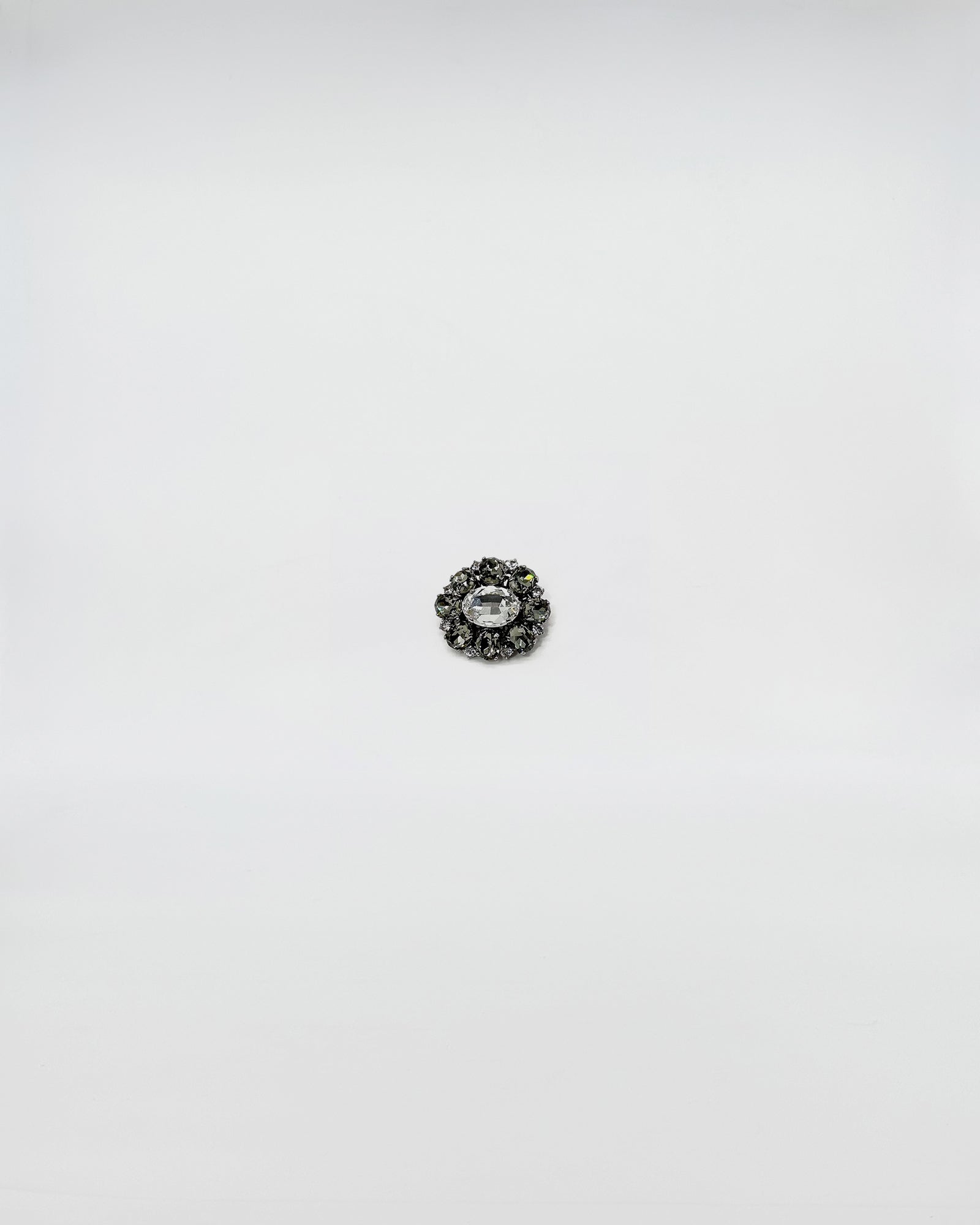 SPILLA IN STRASS FIORE MEDIO, elegante spilla con cristalli luminosi su sfondo bianco.