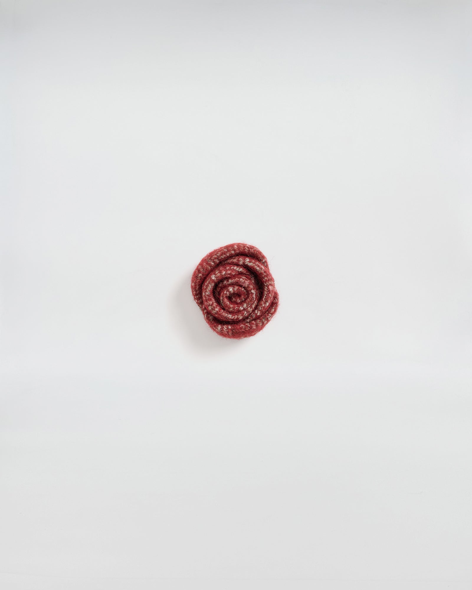 Spilla rosa in lana, accessorio elegante e contemporaneo, perfetto per giacche e cappotti.