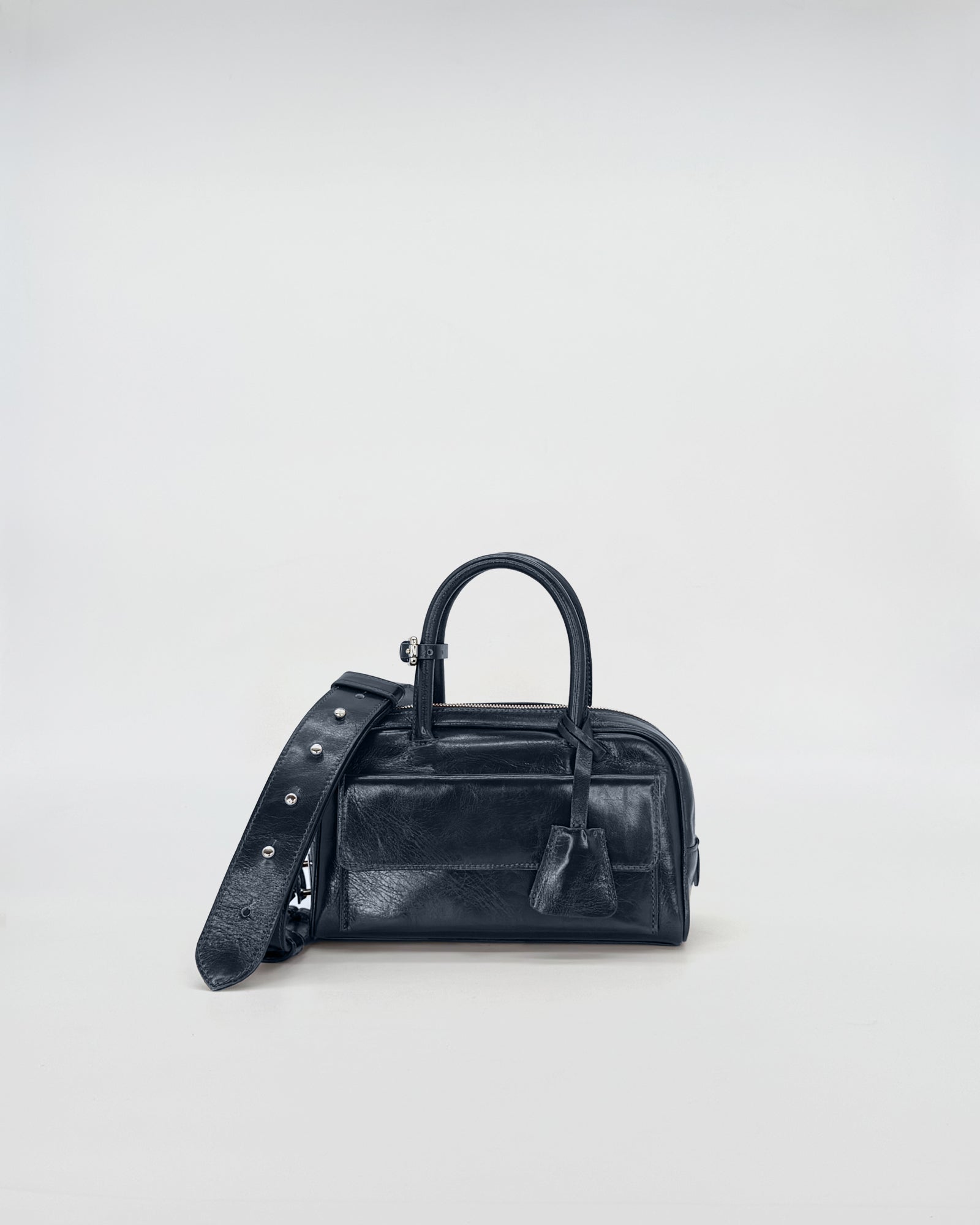 Zoe Mini Vitello Semilucido black handbag with adjustable strap on a light background.
